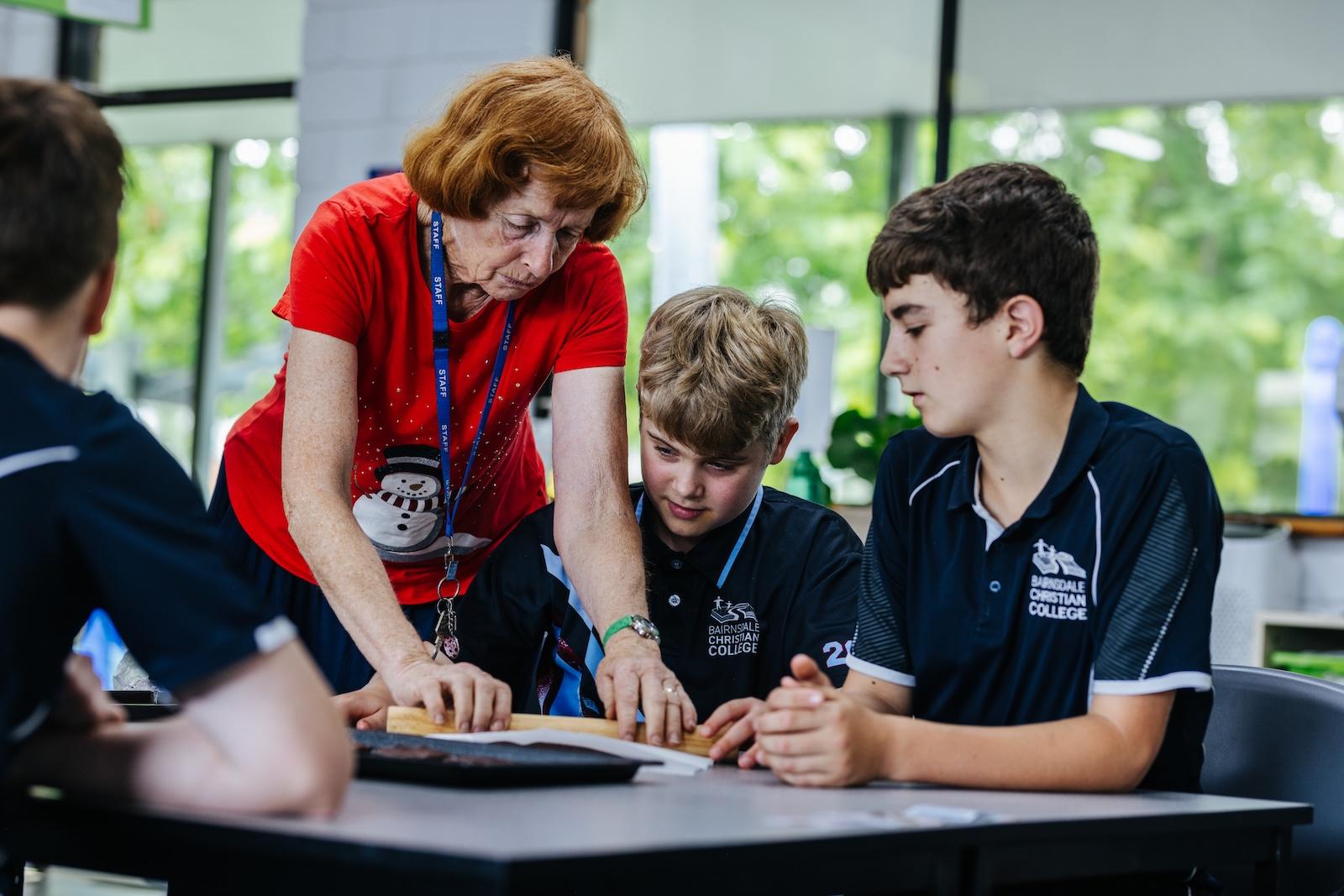 A food technology teacher supporting two upper primary students during a practical lesson at ACC Bairnsdale.
