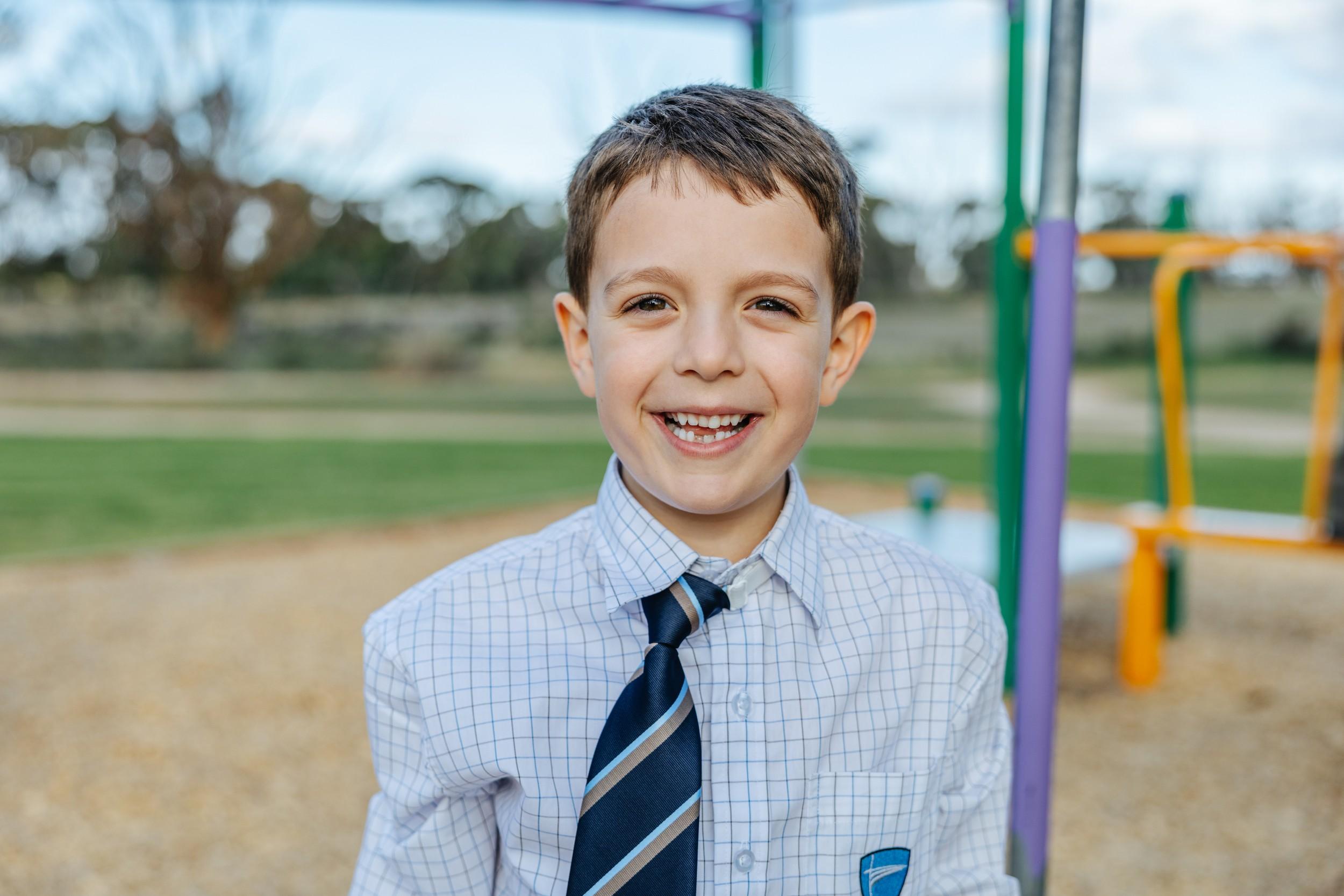 A smiling primary school student at ACC Bairnsdale outdoors on the school playground.