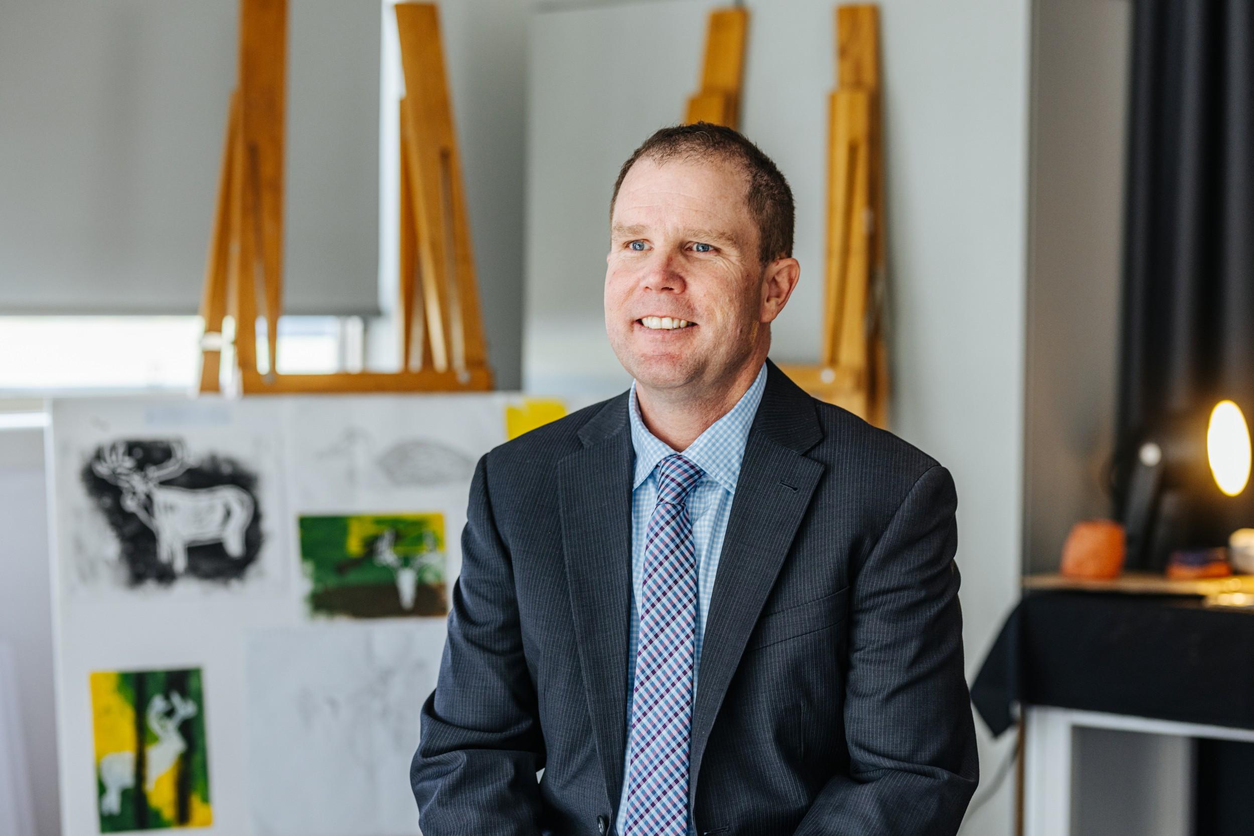 Principal Craig Dredge in a suit and tie in the art room at ACC Bairnsdale in Bairnsdale VIC.