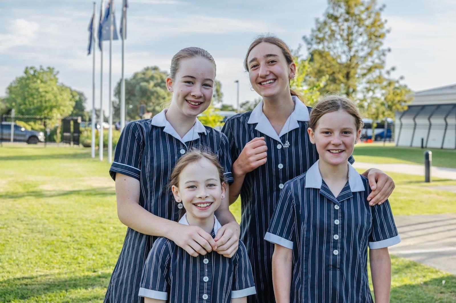 Four female students of varying ages smiling together on the grounds of Australian Christian College Benalla.