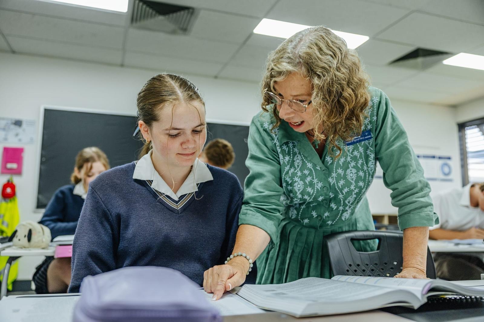 A dedicated teacher at ACC Benalla provides personalised guidance to a female high school student in a modern classroom, fostering a love of learning.