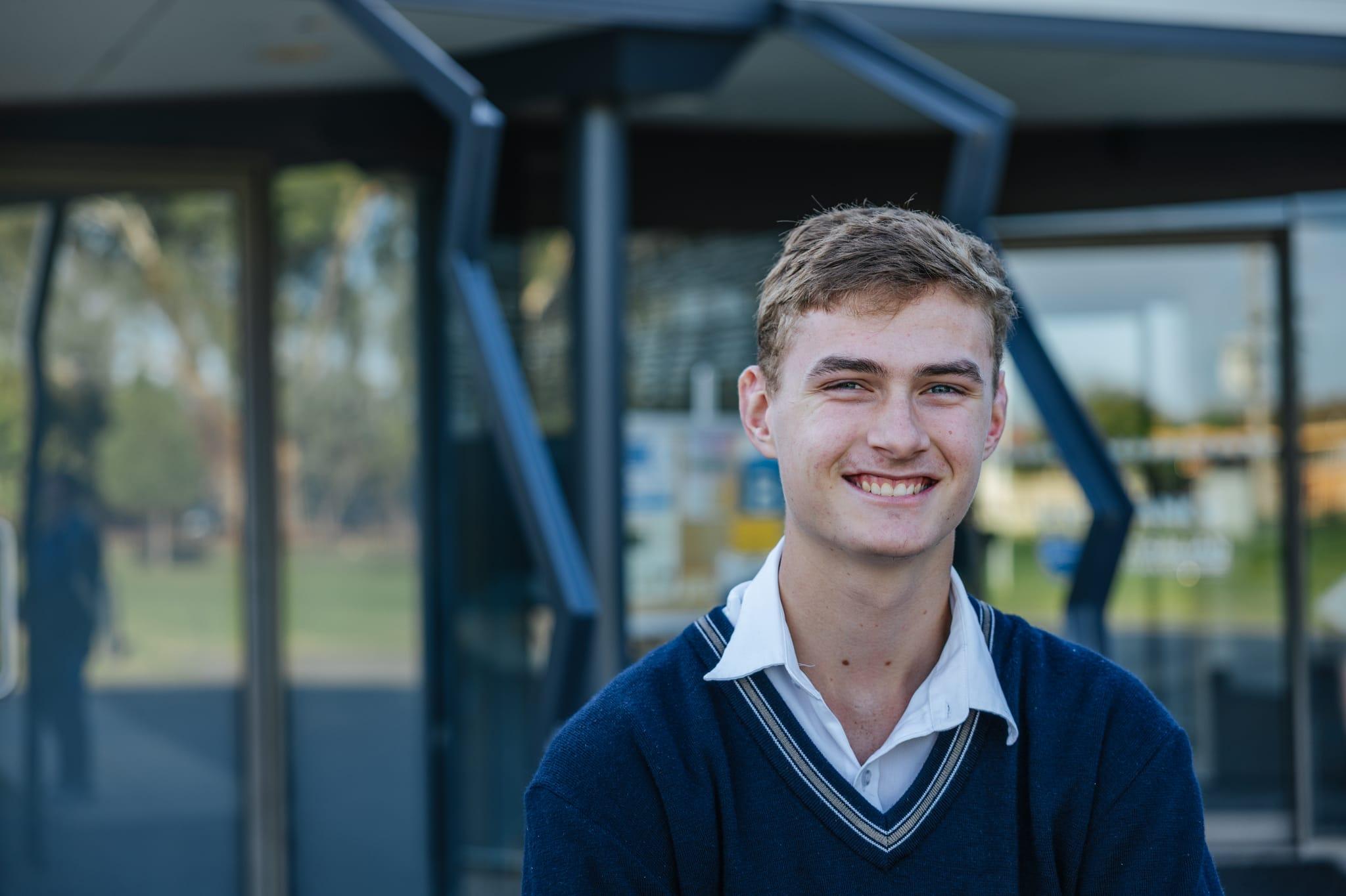 A smiling male high school student in uniform at Australian Christian College Benalla, serving as the hero image for the contact page.