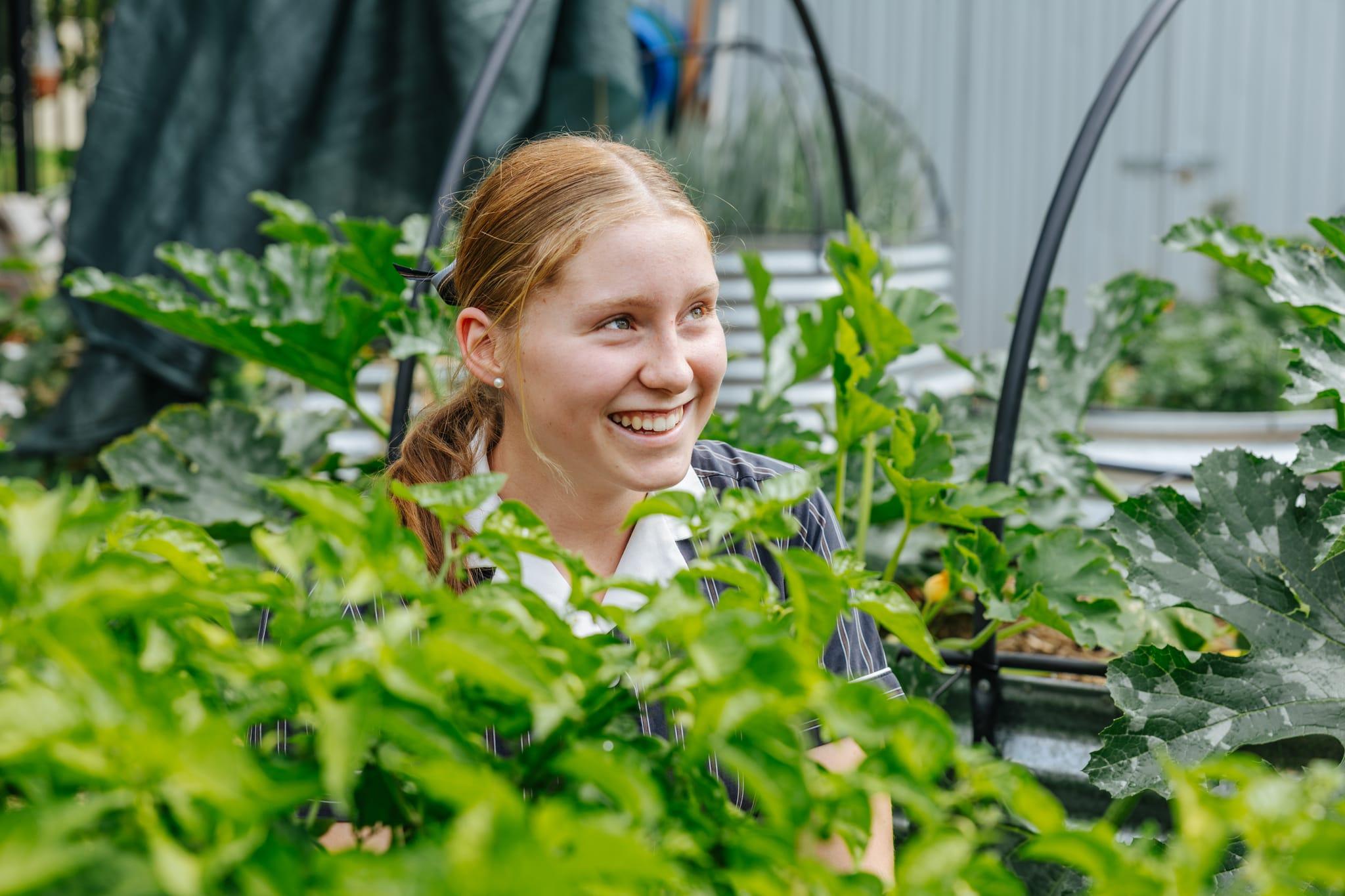 Happy student smiling in the ACC Benalla vegetable garden, highlighting agricultural and outdoor learning programs.