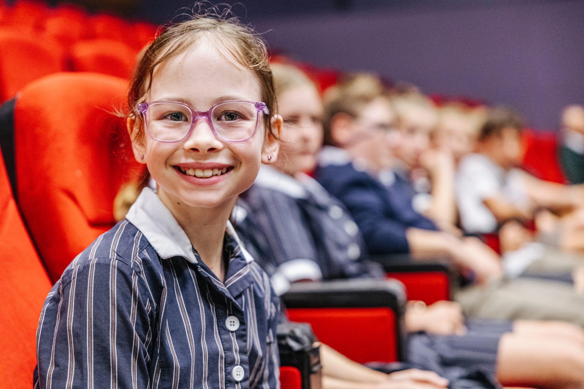 Smiling young student with glasses in a school auditorium, representing affordable Christian education at ACC Benalla.