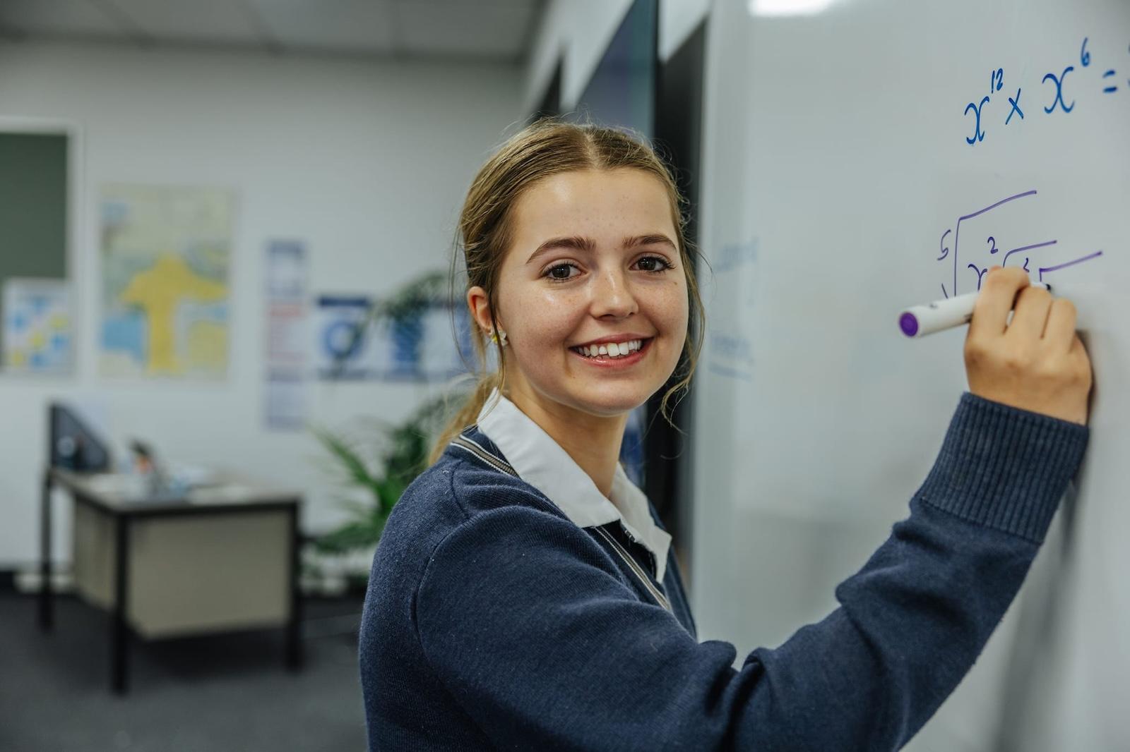A female secondary student writing on a whiteboard during a math class at a Christian school in Victoria.