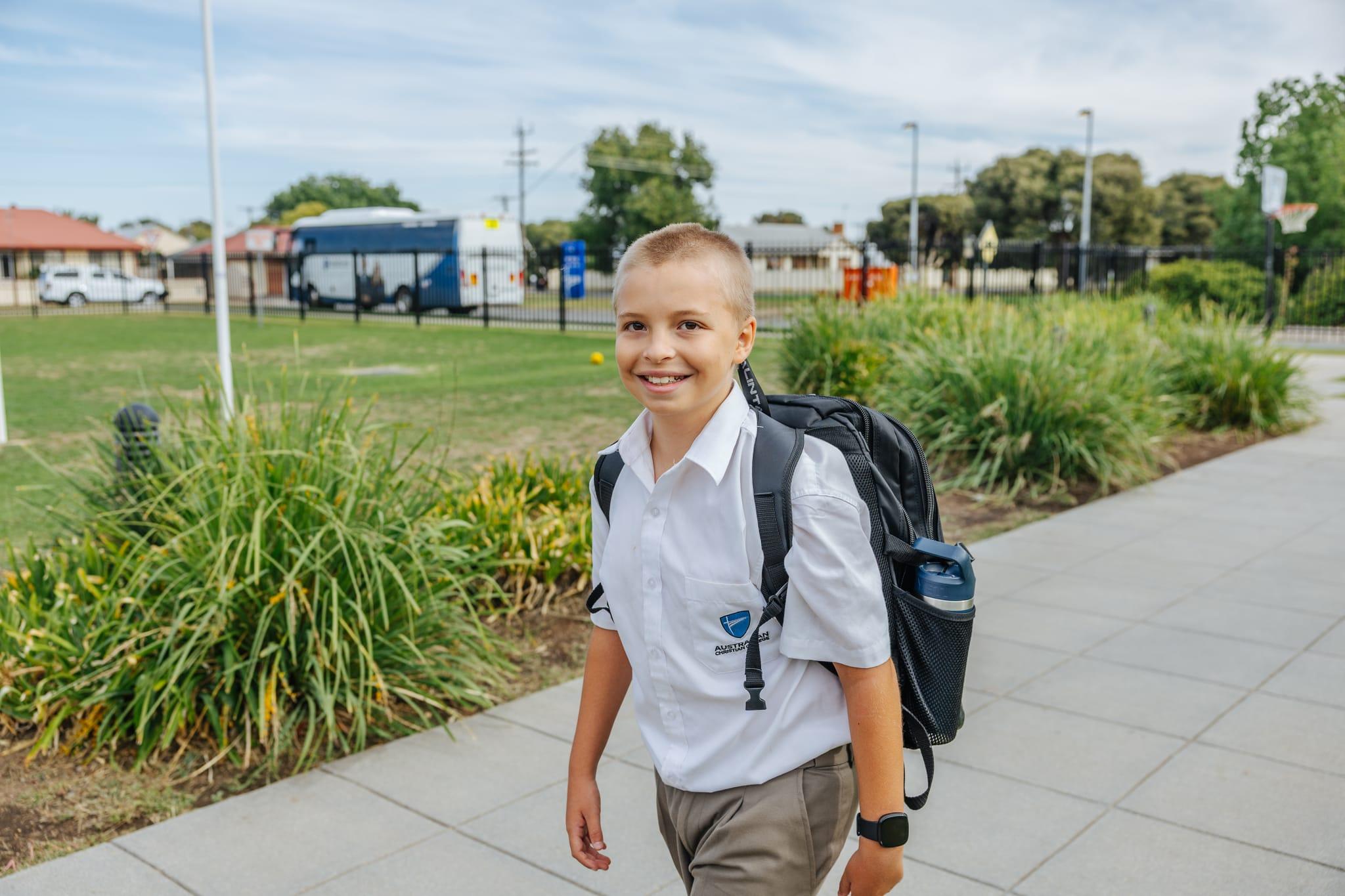 A happy primary school student with a backpack walking on a path at ACC Benalla, ideal for showcasing school tours.