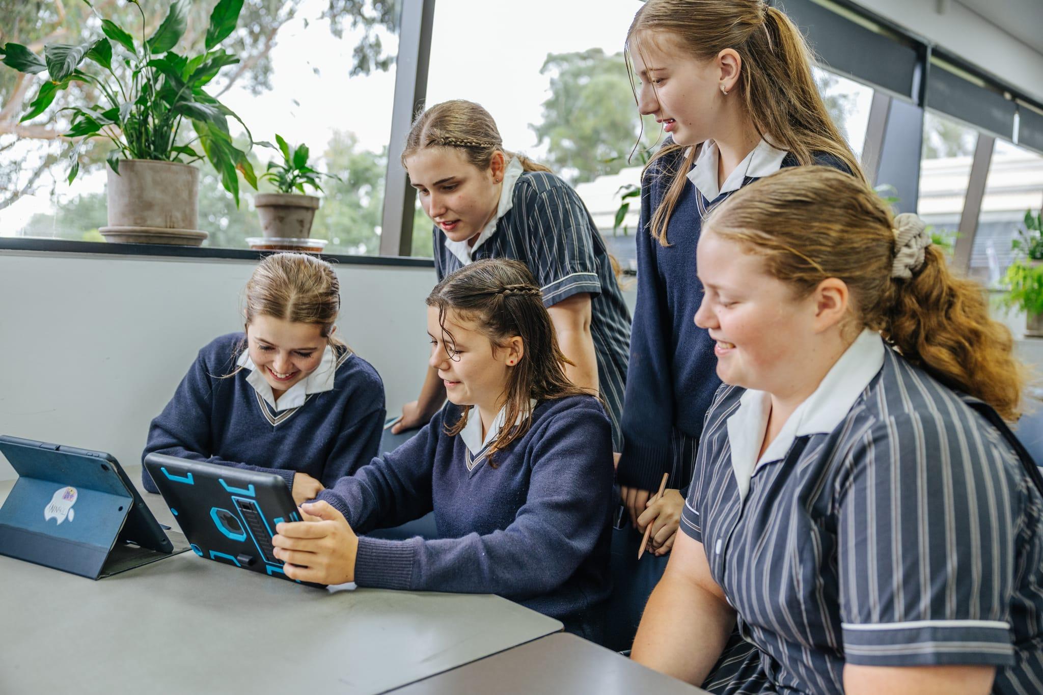 Secondary students using tablets together in a modern classroom, highlighting collaborative learning at a rural Christian school in Victoria.