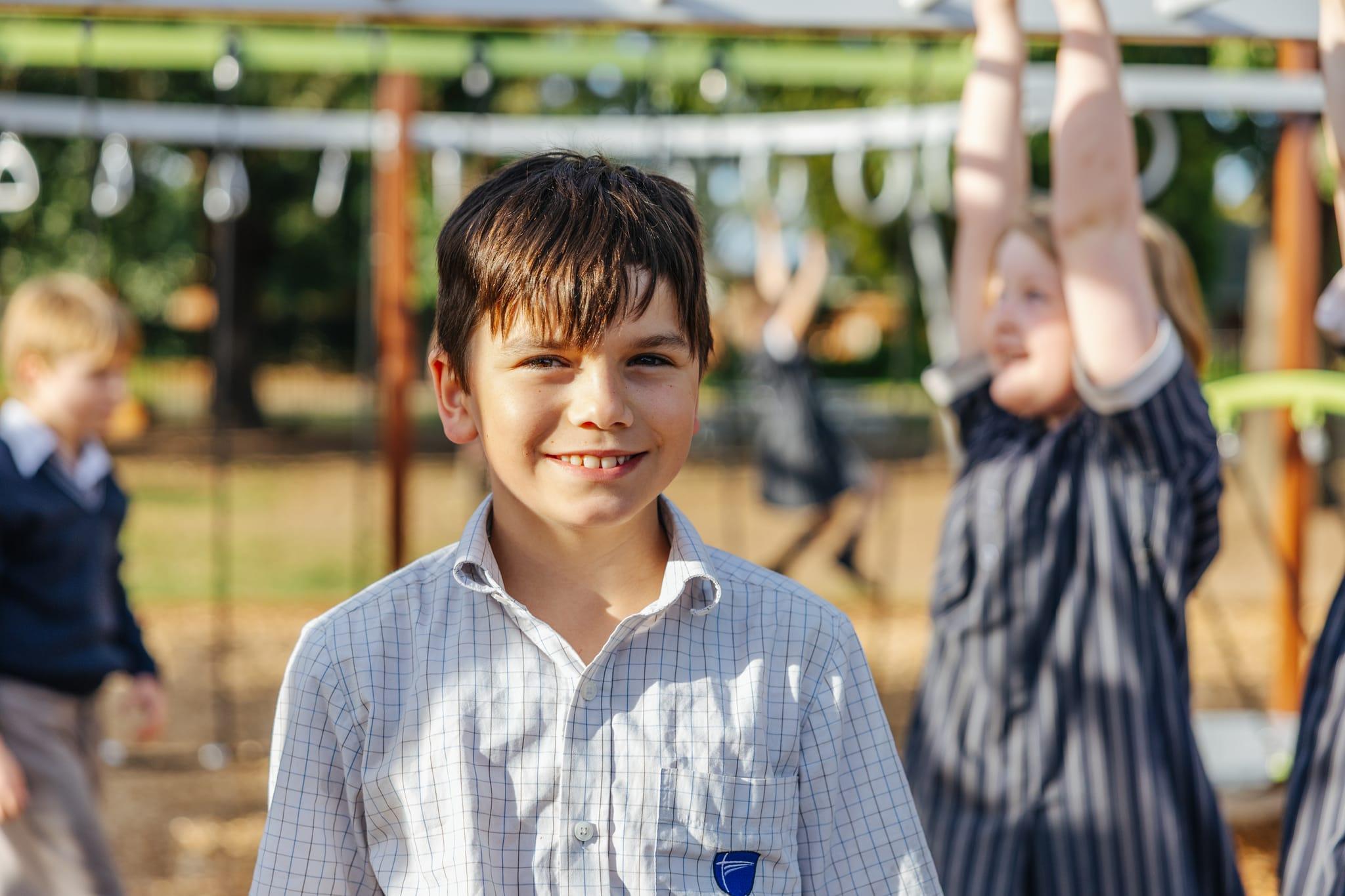 Happy primary school student smiling in front of a playground at Australian Christian College Benalla, highlighting affordable K-12 education.