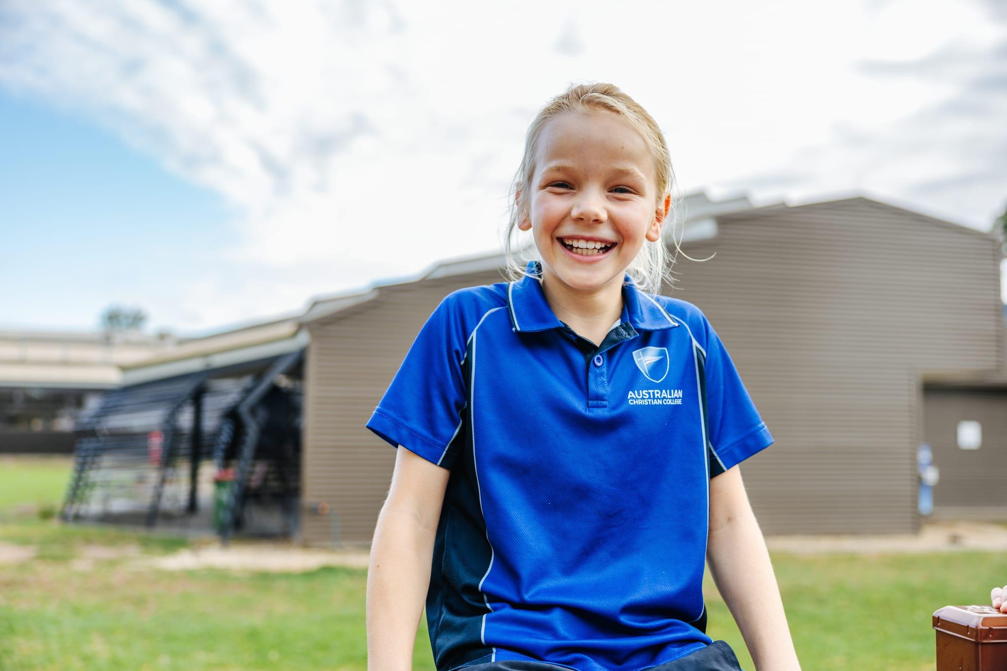 A cheerful, understood, primary school student in a blue sports uniform at Australian Christian College Benalla, Victoria.