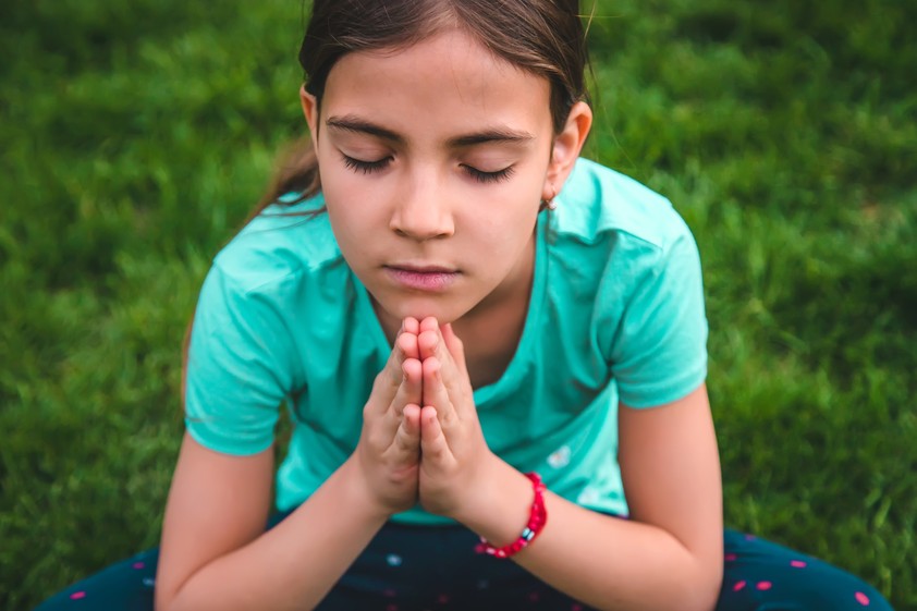 Girl with eyes closed praying outside