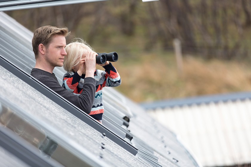Father and son looking through rooflight with binoculars