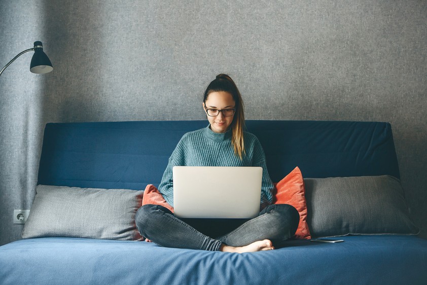 Girl sitting on bed with laptop studying