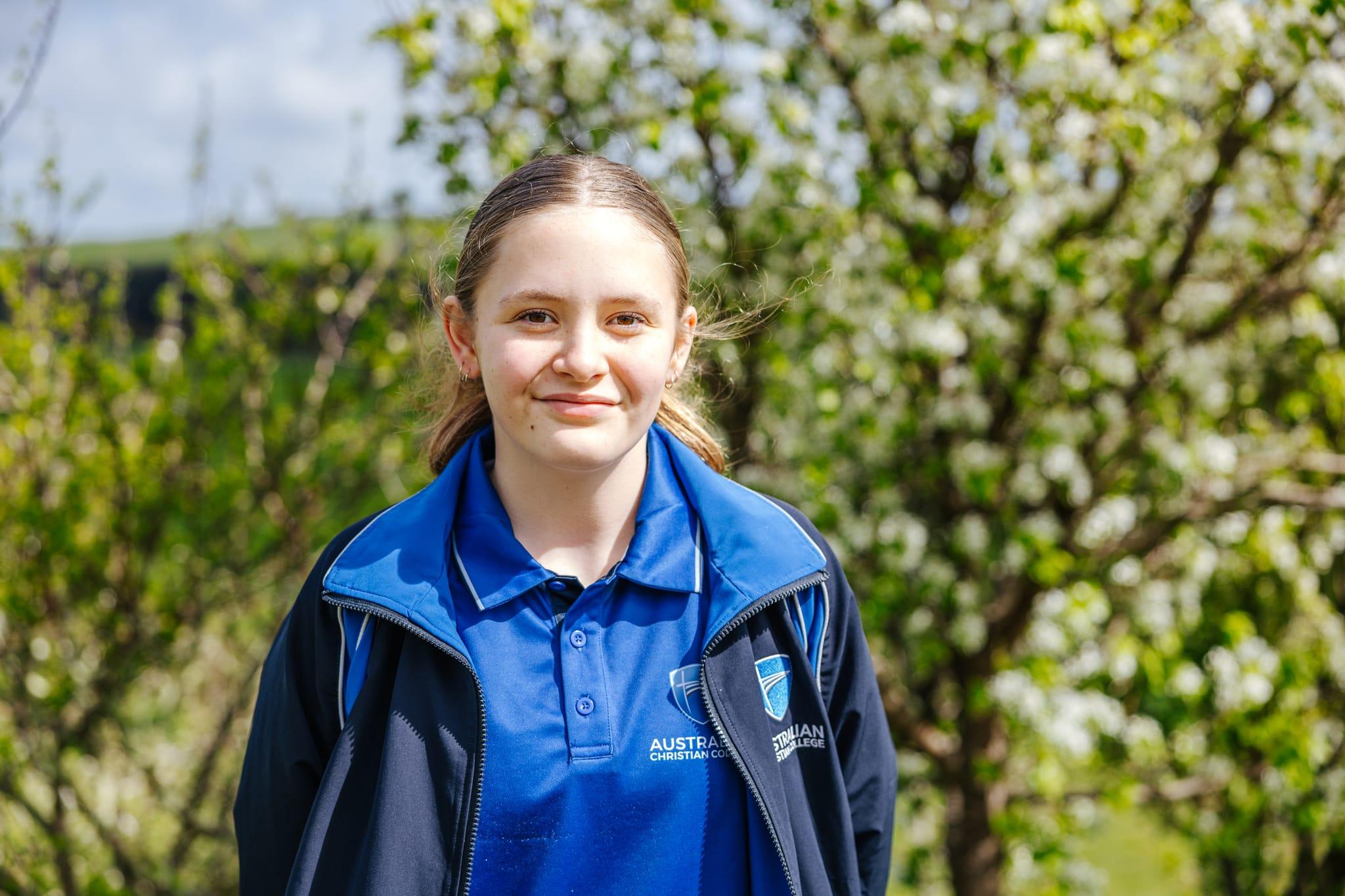 Secondary girl smiling outdoors among blossoms at ACC Burnie Somerset