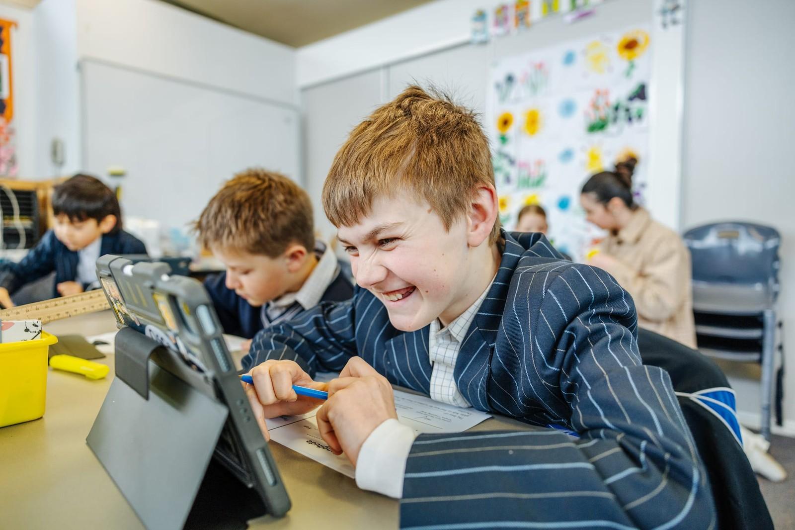 Primary student laughing while working on a tablet during a class activity at ACC Burnie in Tasmania