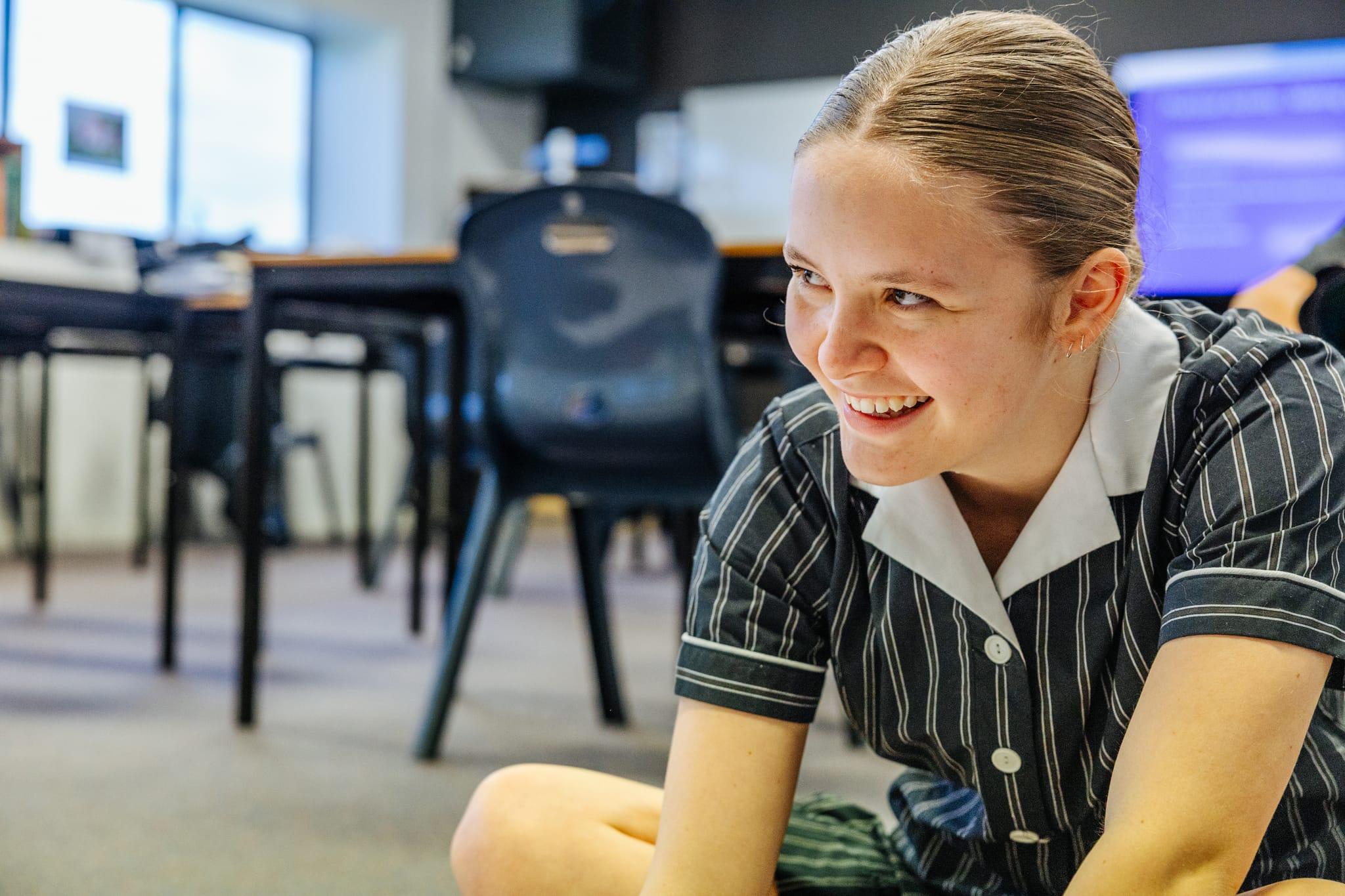 Secondary student in uniform smiling in a classroom at Australian Christian College Burnie