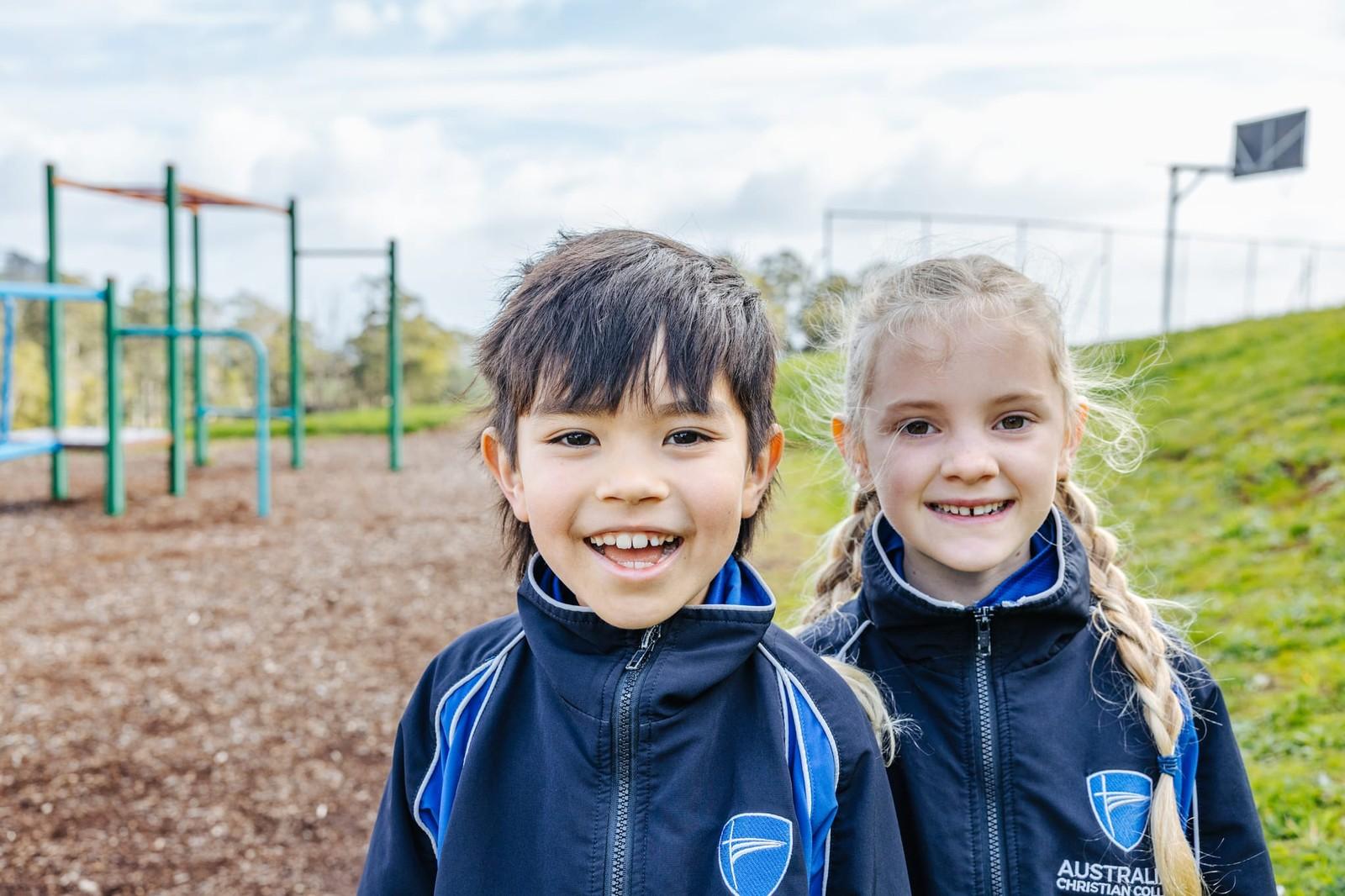 A secondary student in striped school uniform smiling beside a blossoming white-flower tree at ACC Burnie in Tasmania.