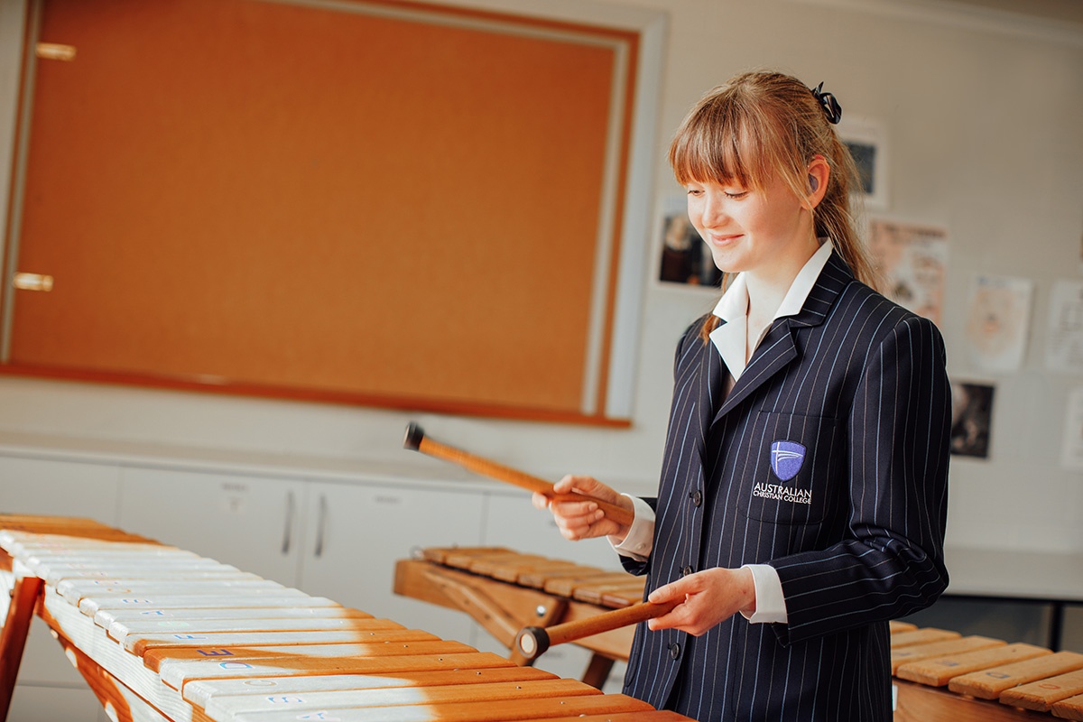 Secondary girl wearing blazer playing marimba in music clasroom