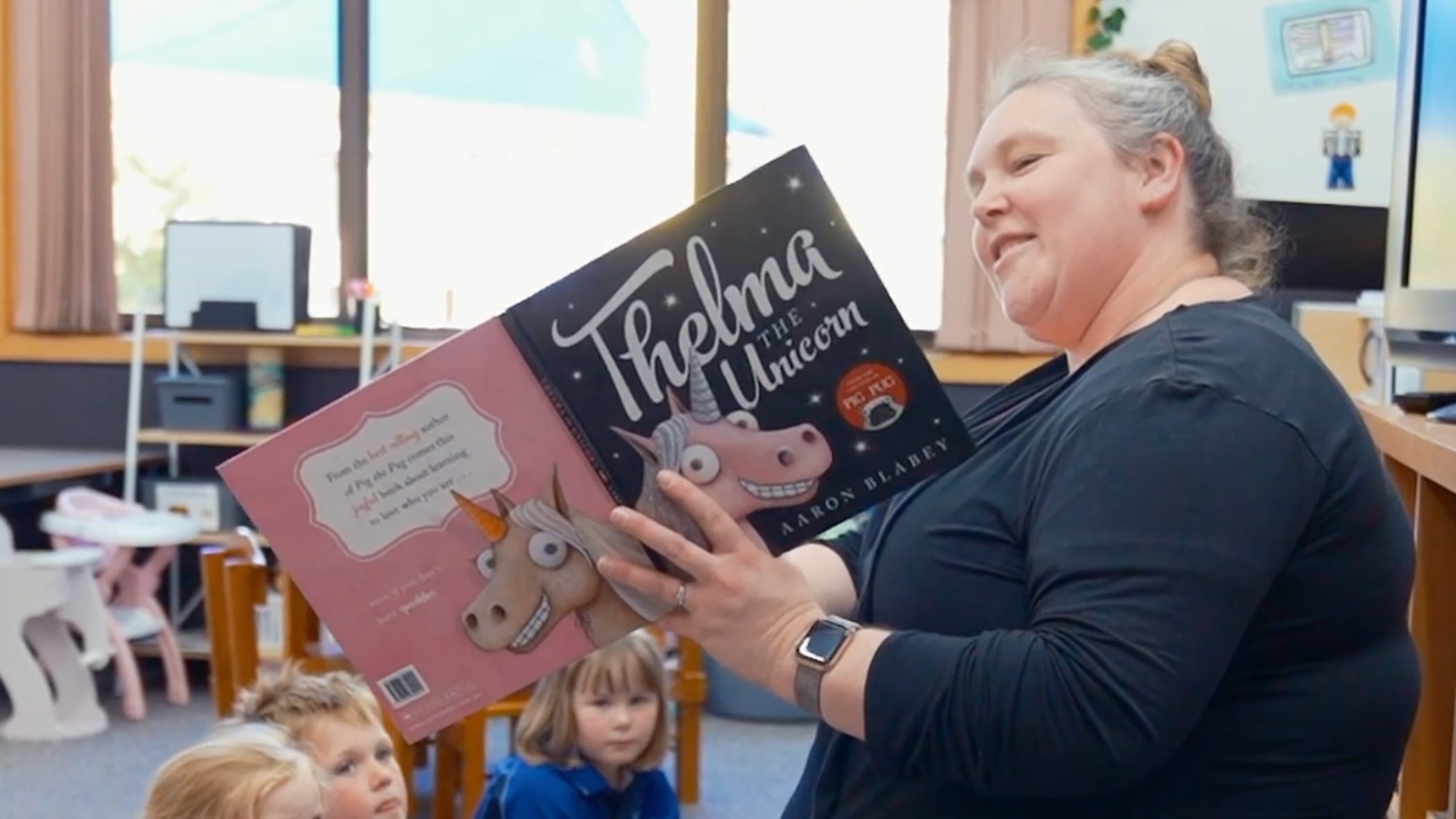 teacher reading book to class of kindy students