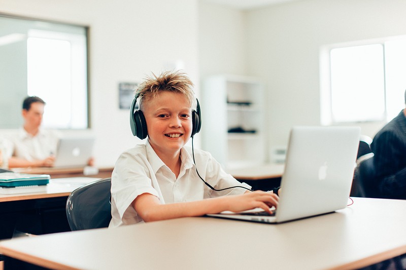 Junior High School student wearing headphones while using laptop