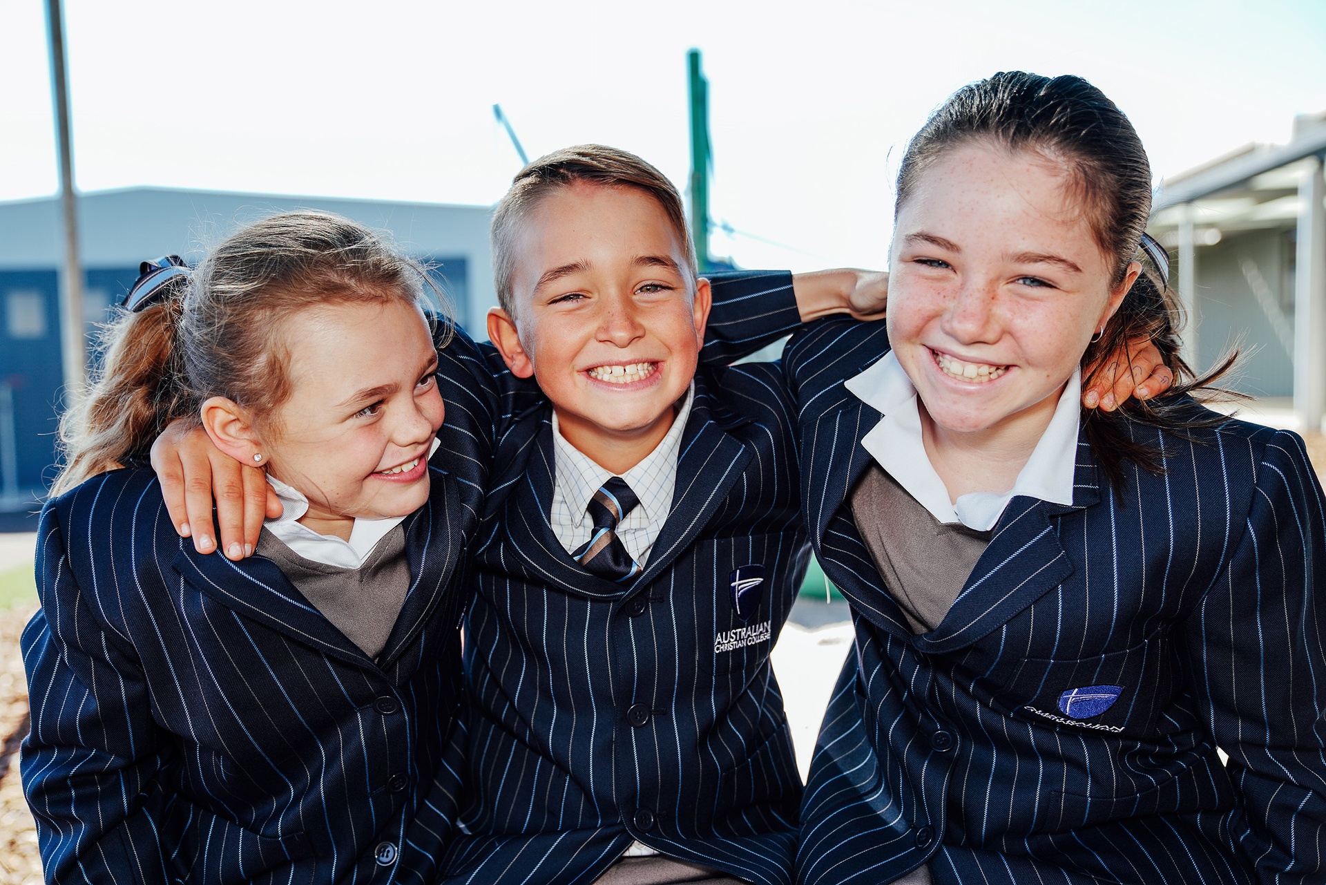 3 primary students at ACC Burnie laughing with arms around one another