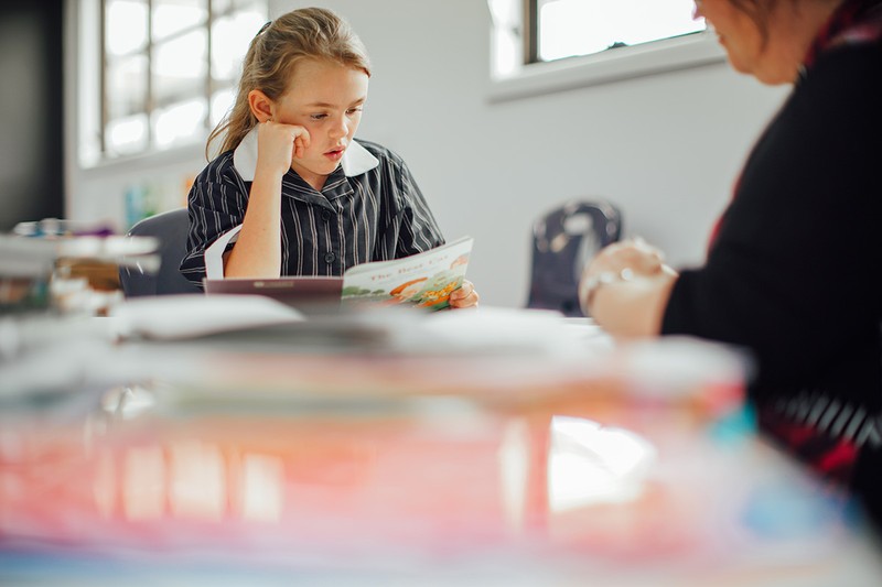 girl in ACC Burnie classroom focusing intently while reading book