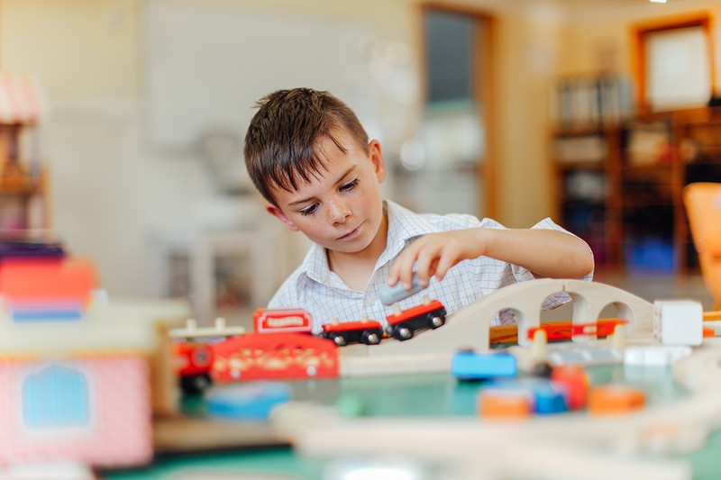 boy play with toy trains in classroom