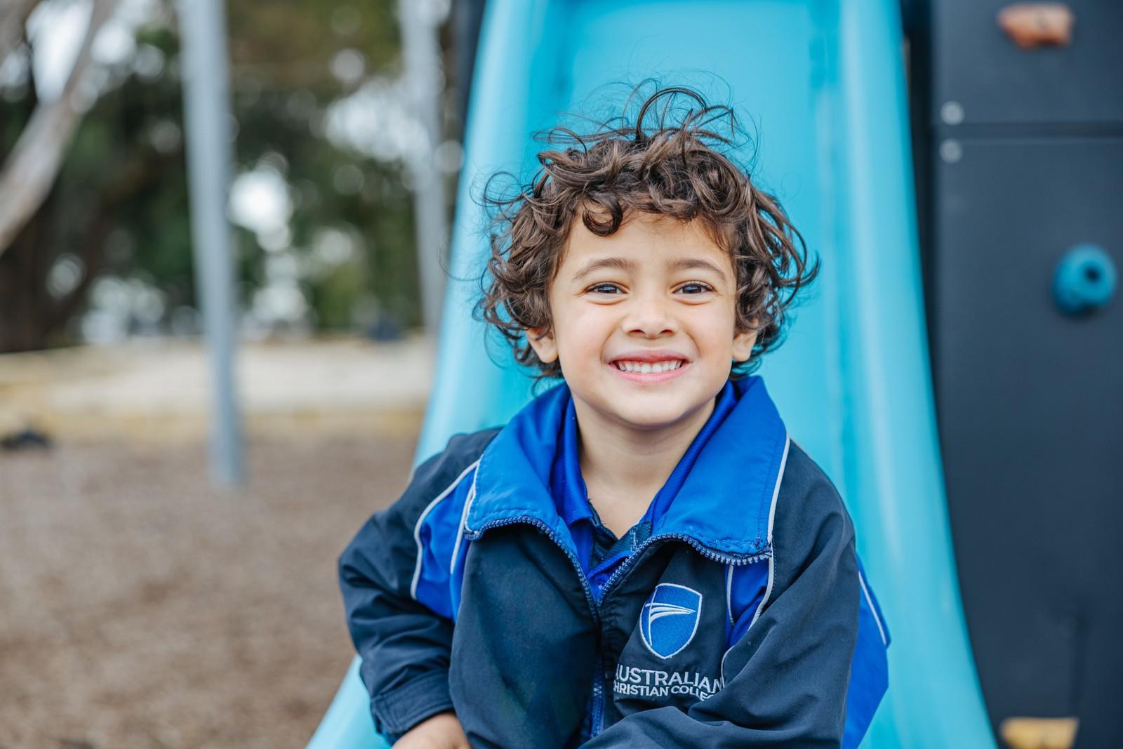 Young child plays on the slide and play equipment outdoors, developing physical coordination at Darling Downs WA.