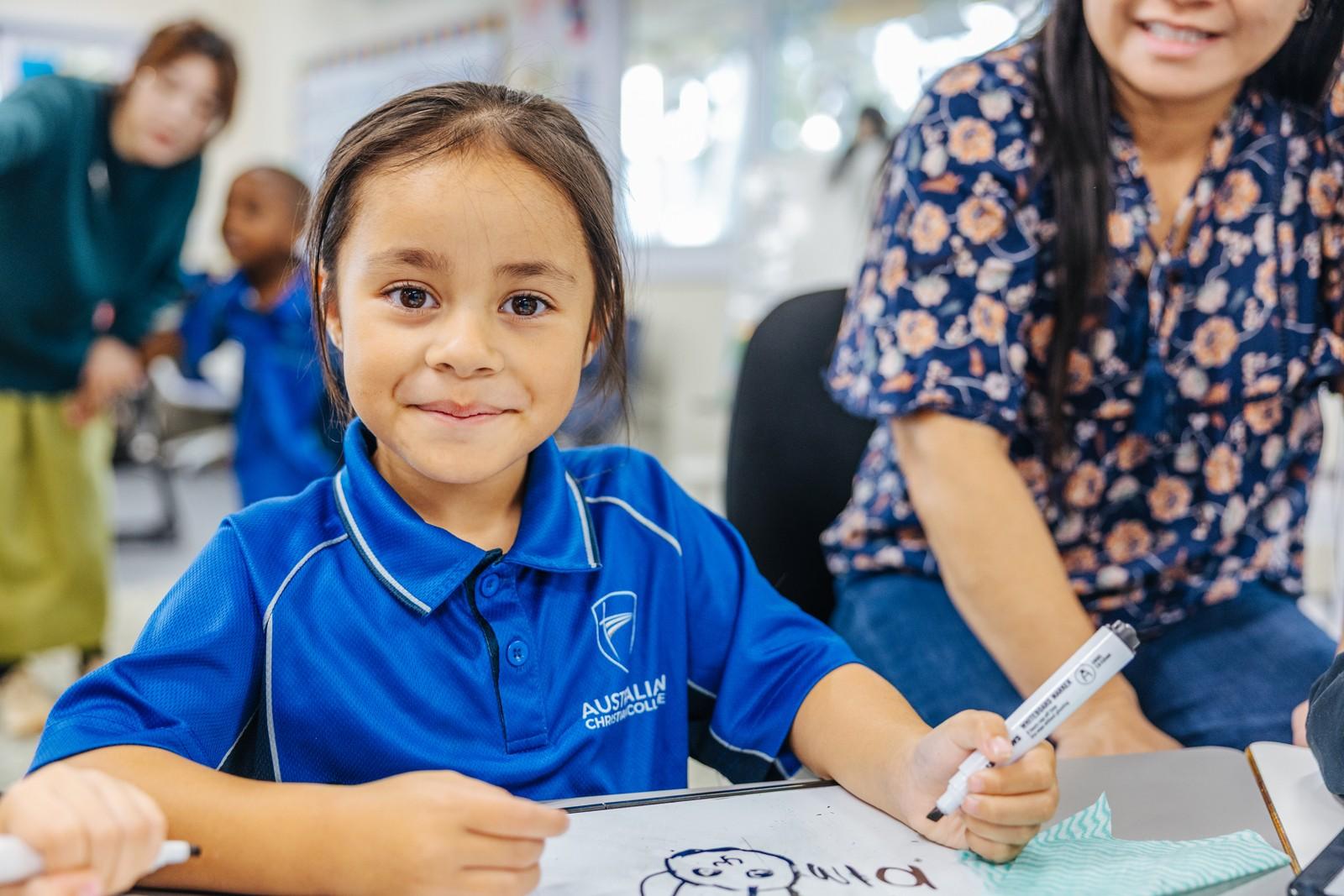Young learner writes numbers and shapes on a whiteboard, building early literacy skills at ACC Darling Downs.