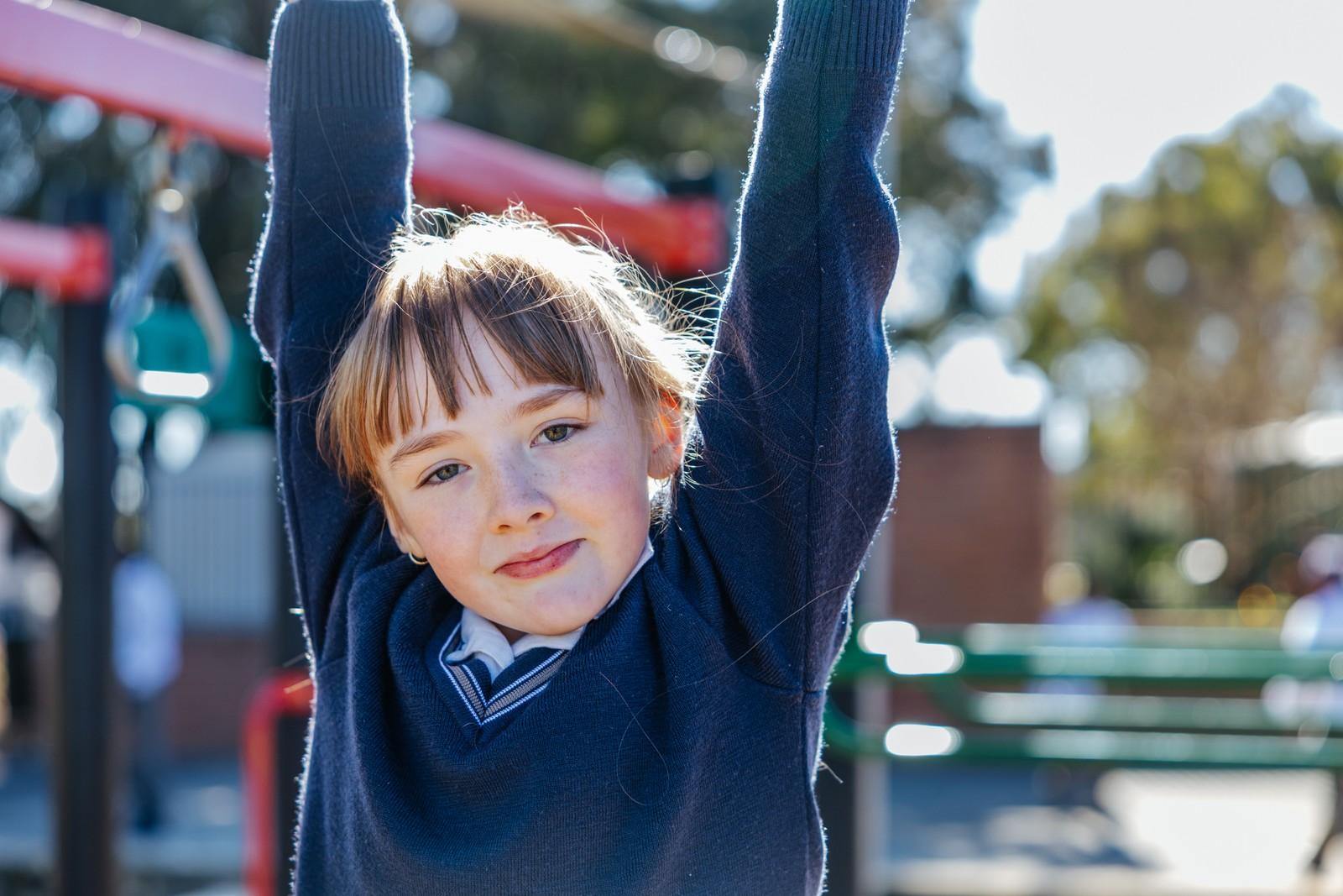 Young primary student playing on the playground monkey bars at Darling Downs on a sunny day