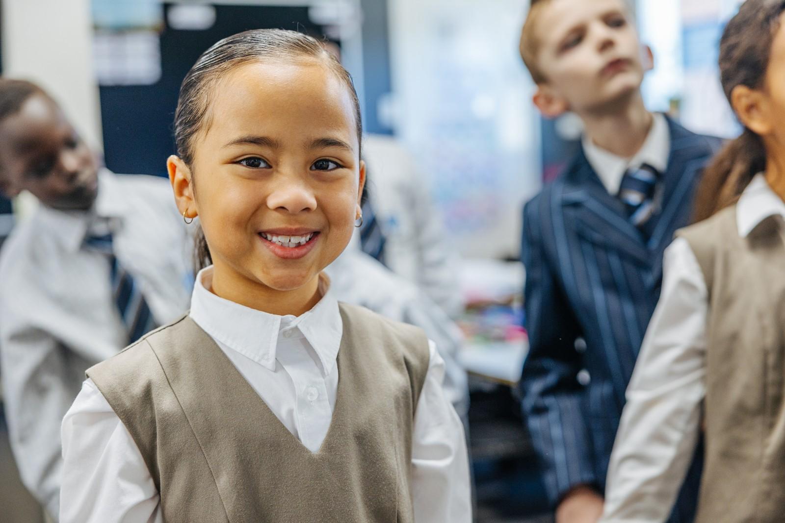 Primary student smiling confidently in a classroom at ACC Darling Downs WA with classmates nearby.