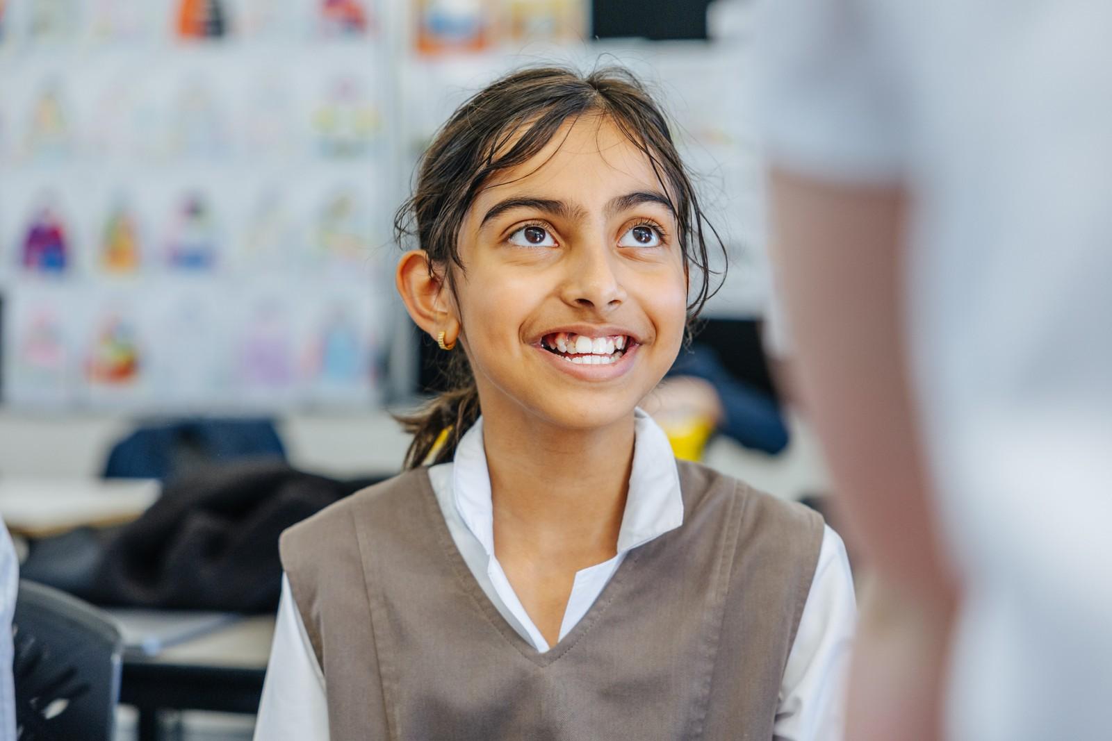A primary student smiles in a classroom, reflecting the joy and confidence that come from creative, hands-on learning at ACC Darling Downs.