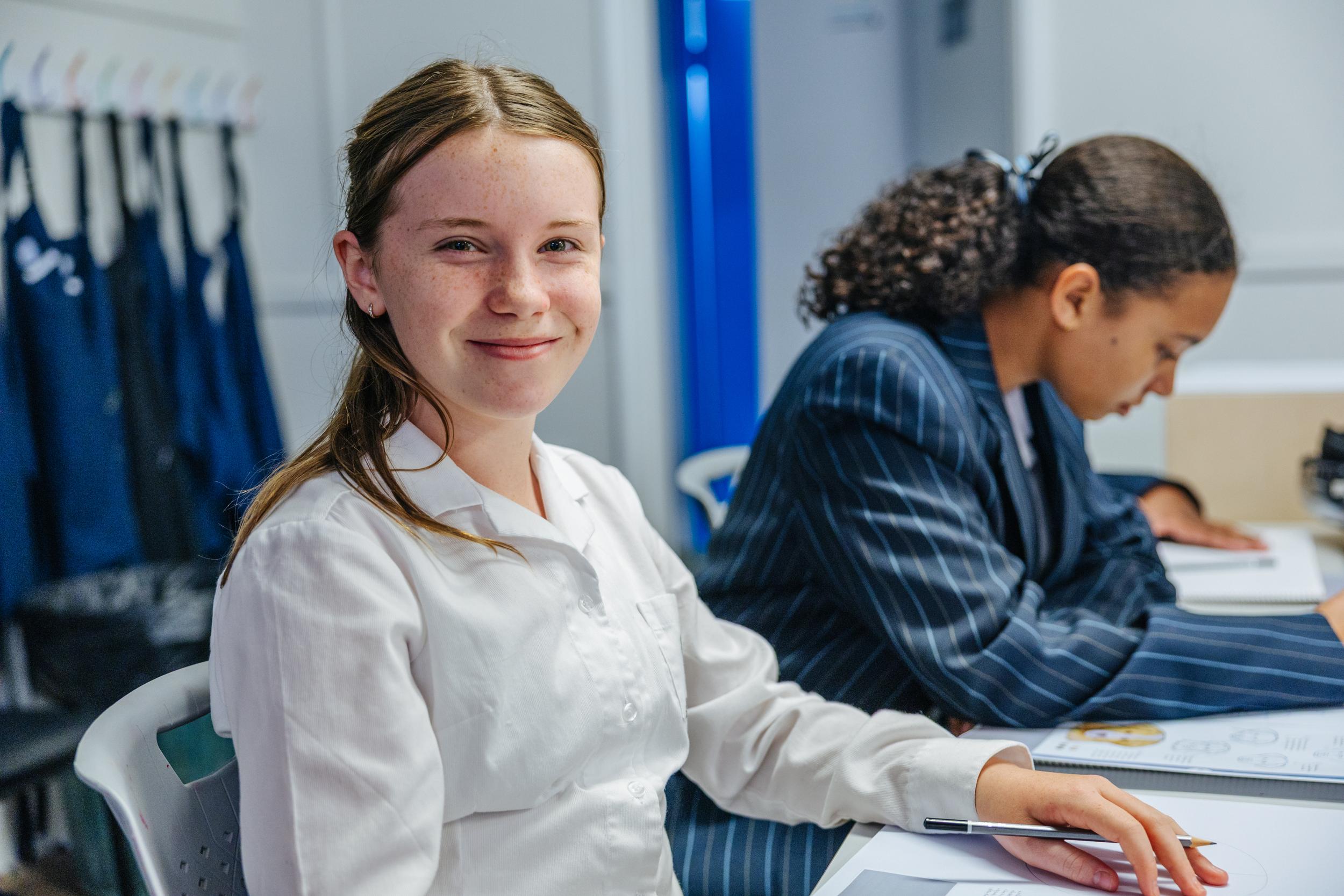 A secondary student in school blazer sits attentively in class, where smaller groups and dedicated teachers connect study to the real world.