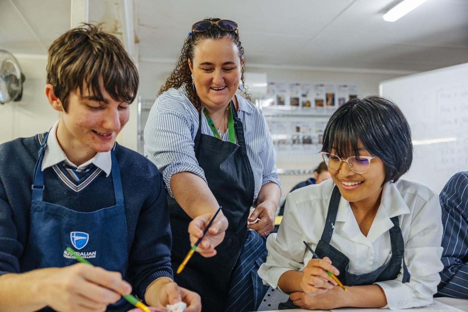 Teacher guiding two secondary students step-by-step through a hands-on practical lesson in class.