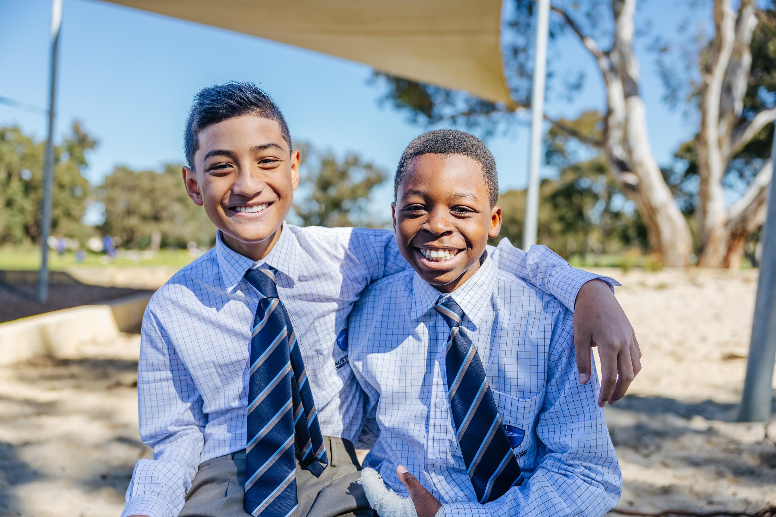 Two smiling ACC Darling Downs students standing together outdoors, at ease within their close school community.