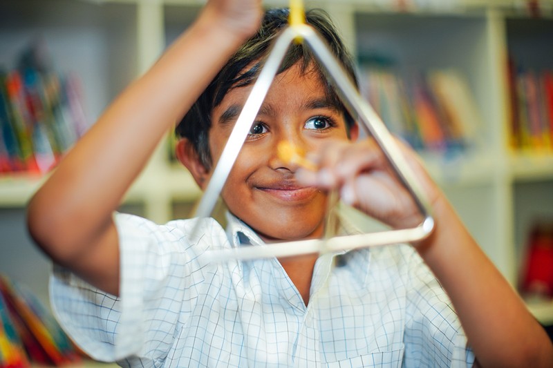 Primary boy at playing triangle instrument at ACC Darling Downs