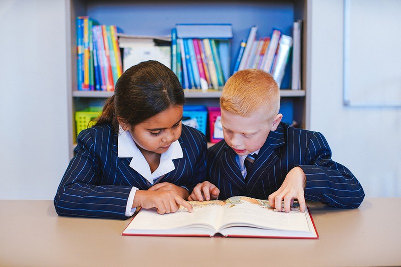 Young boy and girl students reading together