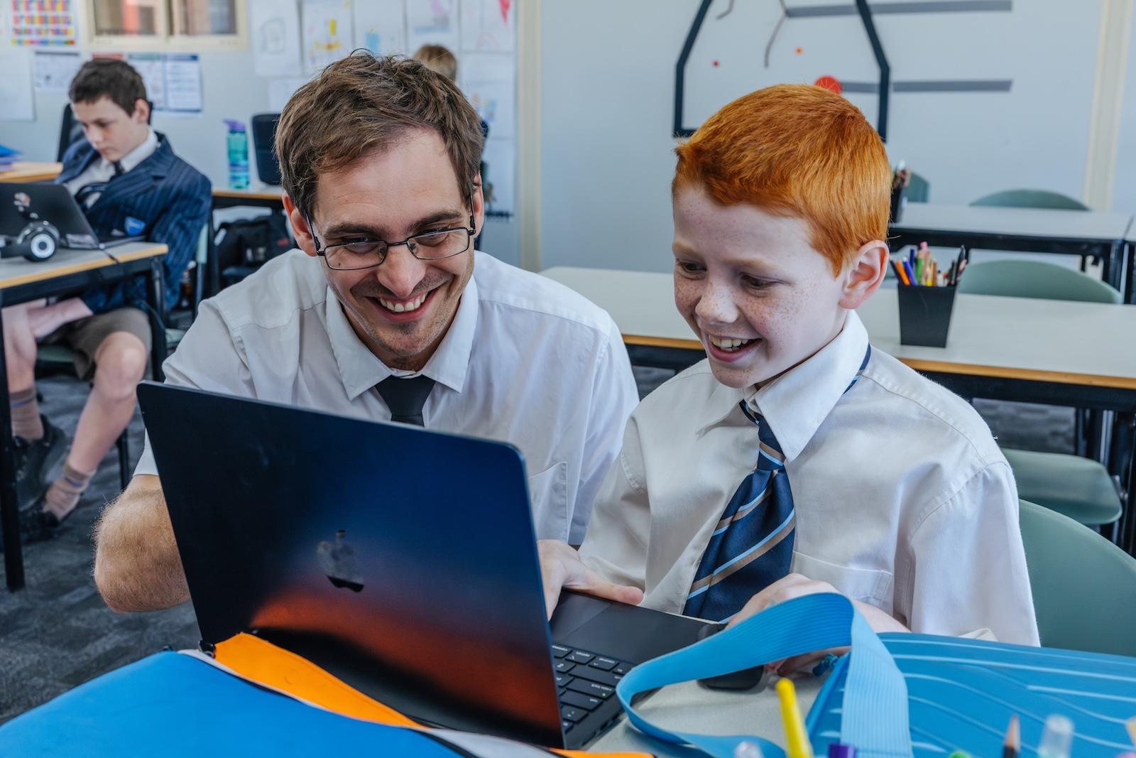 A teacher and student share a moment of success over a laptop—learning grounded in trust, encouragement, and shared values at ACC Echuca.