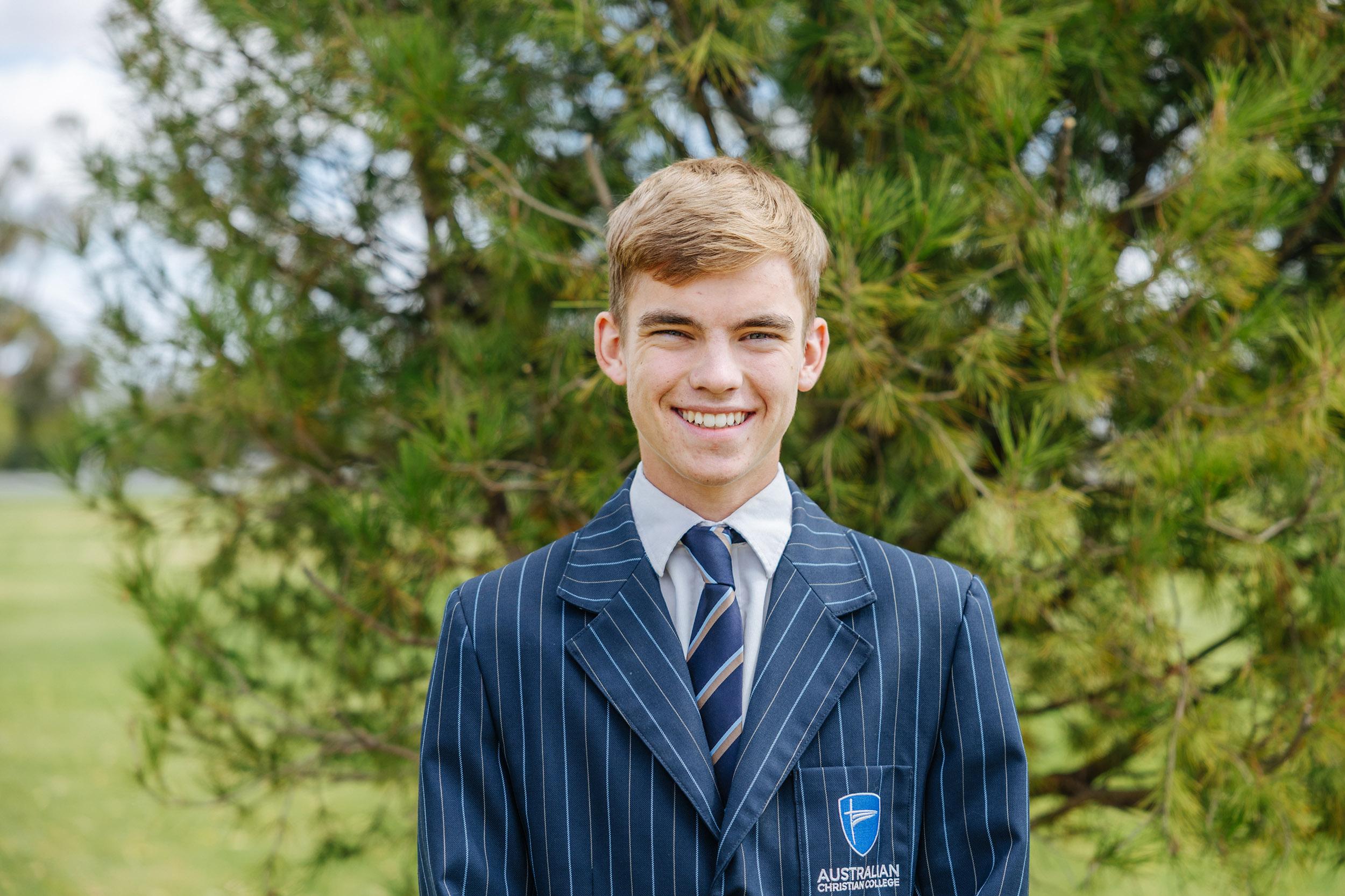 A secondary student stands confidently in uniform outdoors, reflecting the leadership and growth nurtured through high school at ACC Echuca.
