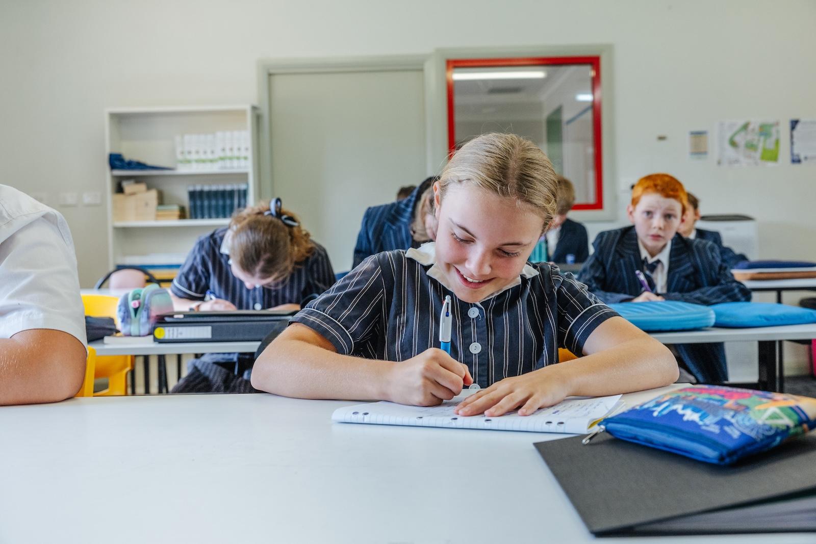 A high school student concentrates on written work in class while peers work independently, reflecting the growing maturity and academic ownership fostered at ACC Echuca.