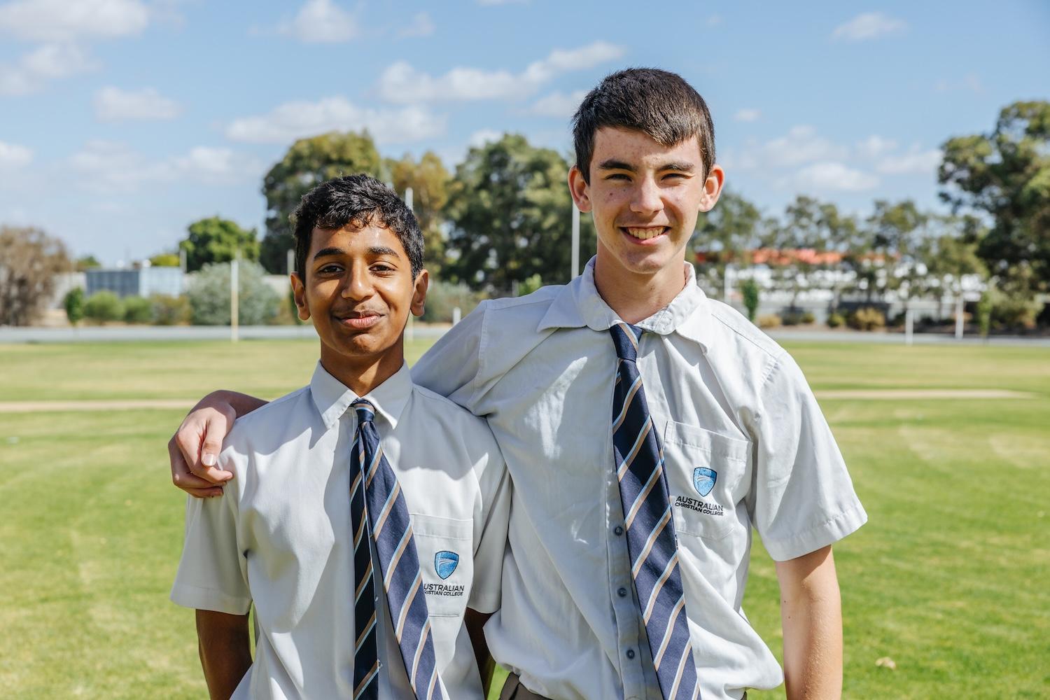 Two secondary students standing arm in arm on the school oval at ACC Echuca, reflecting strong friendships and a culture where every student is personally known.