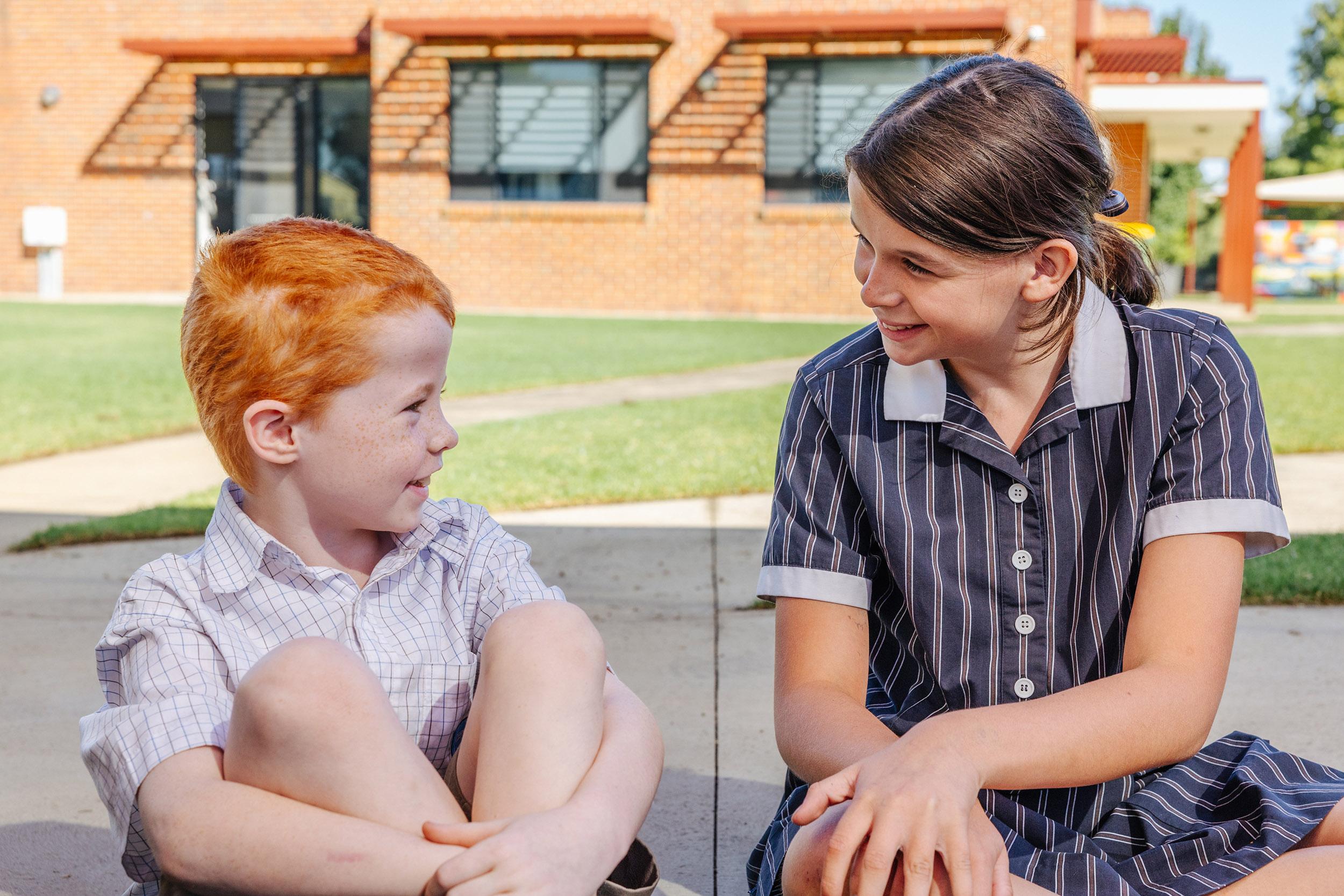 Older and younger students chatting warmly outside a red-brick school building at a Christian school in regional Victoria