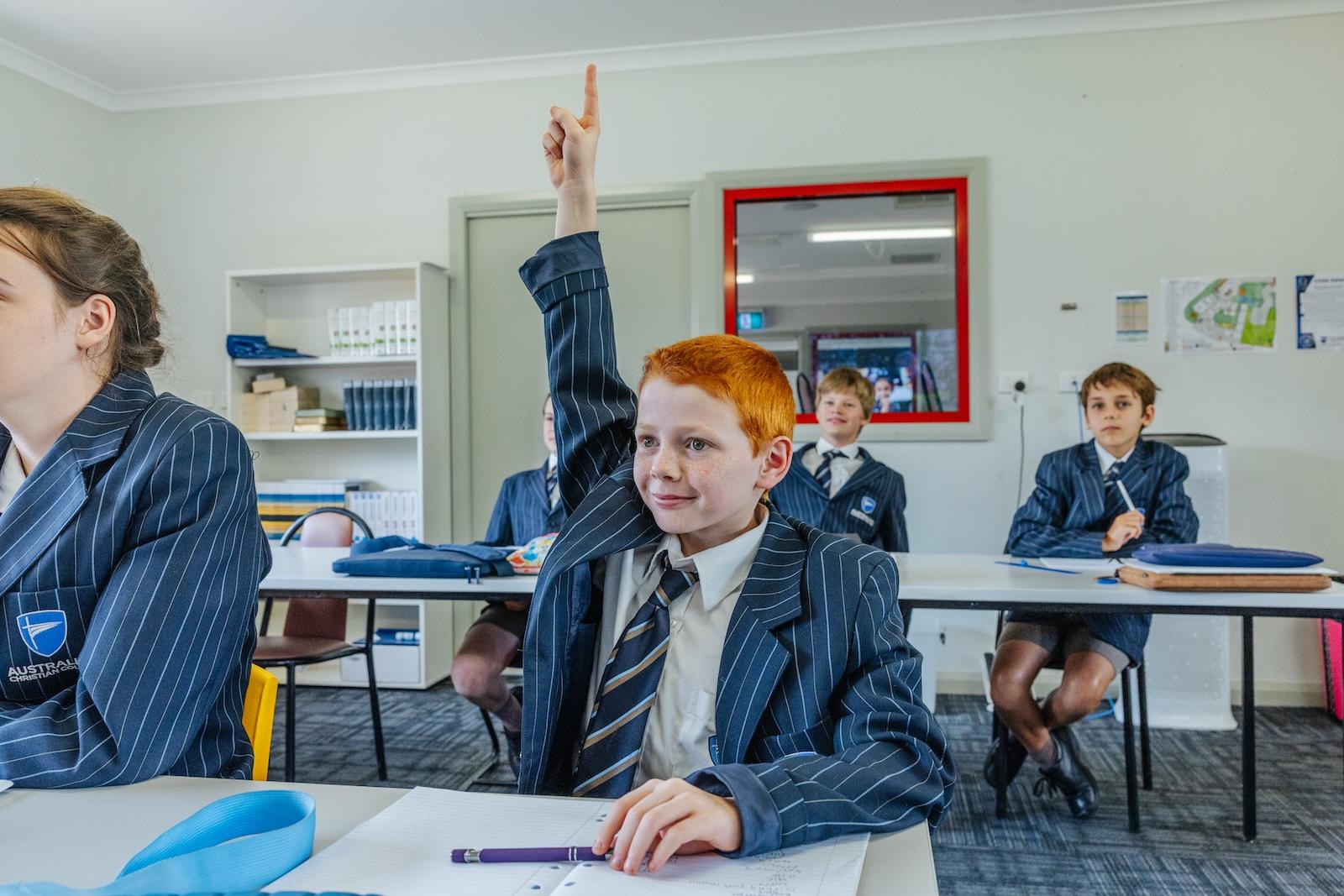 A student raises his hand in class, reflecting ACC Echuca’s clear policies and open communication between staff, students, and families.