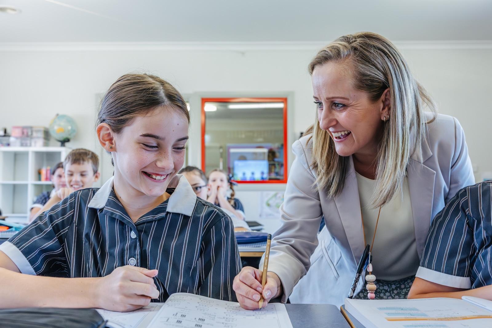 Female teacher supporting smiling student during class at ACC Echuca, illustrating Christ-centred education and positive teacher-student relationships.