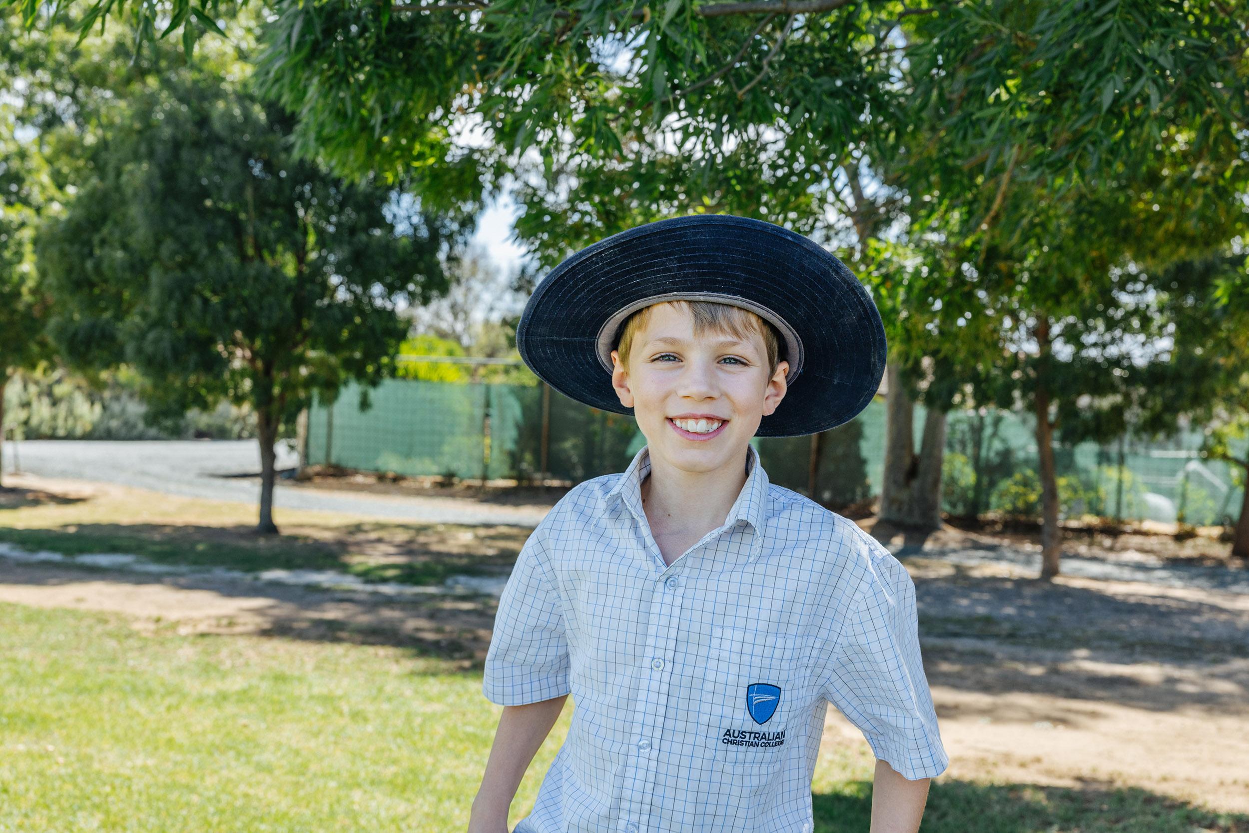 Smiling primary school boy in uniform and sunhat at ACC Echuca, embodying joy and balance in a Christ-centred outdoor learning environment.