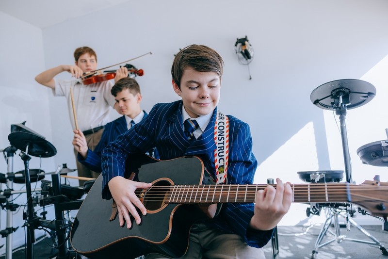 ACC Echuca student in blazer playing guitar