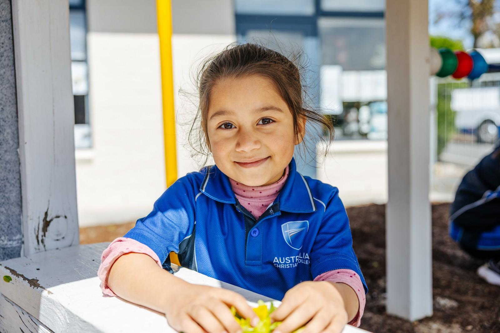 A primary student in ACC uniform smiles confidently outside, reflecting the safety and support of strong school relationships.