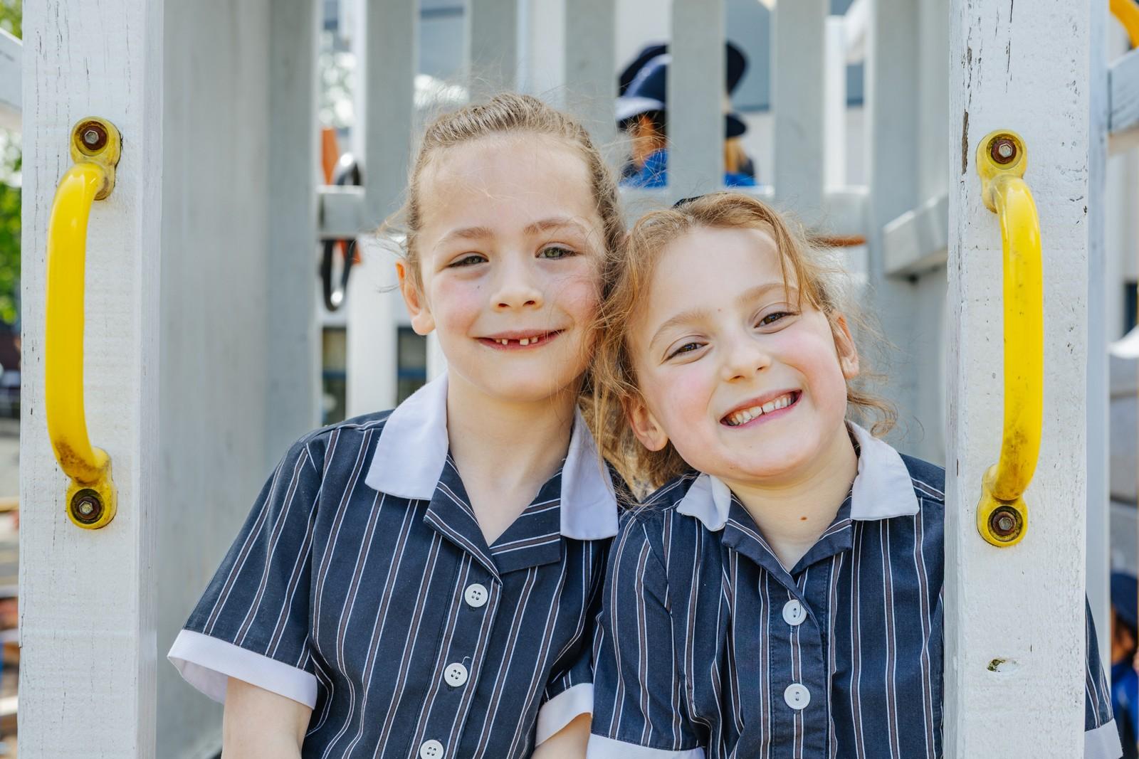 Two smiling primary students in school uniform at the Geilston Bay playground