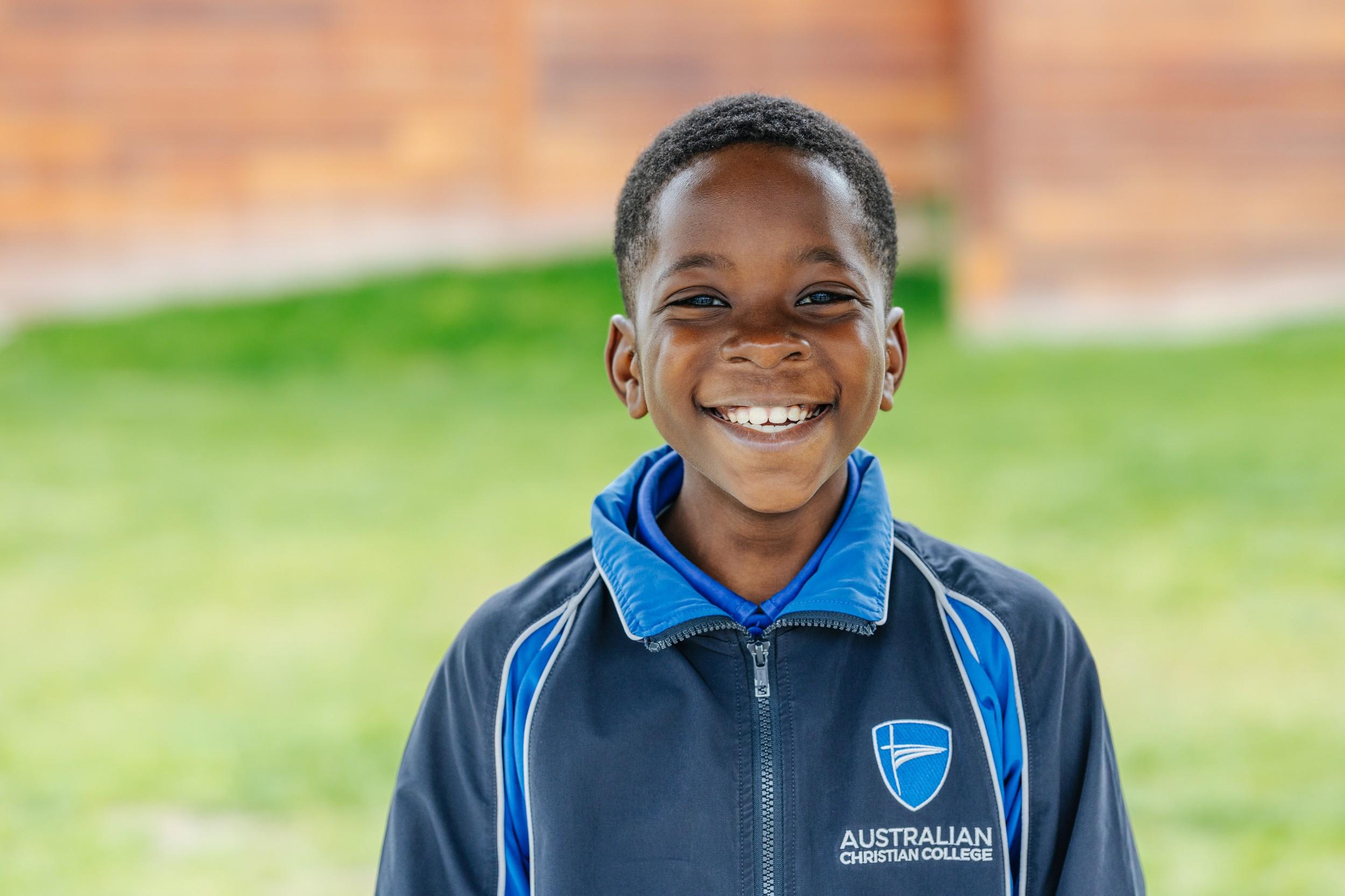 Smiling primary student in ACC Hobart uniform outdoors on campus