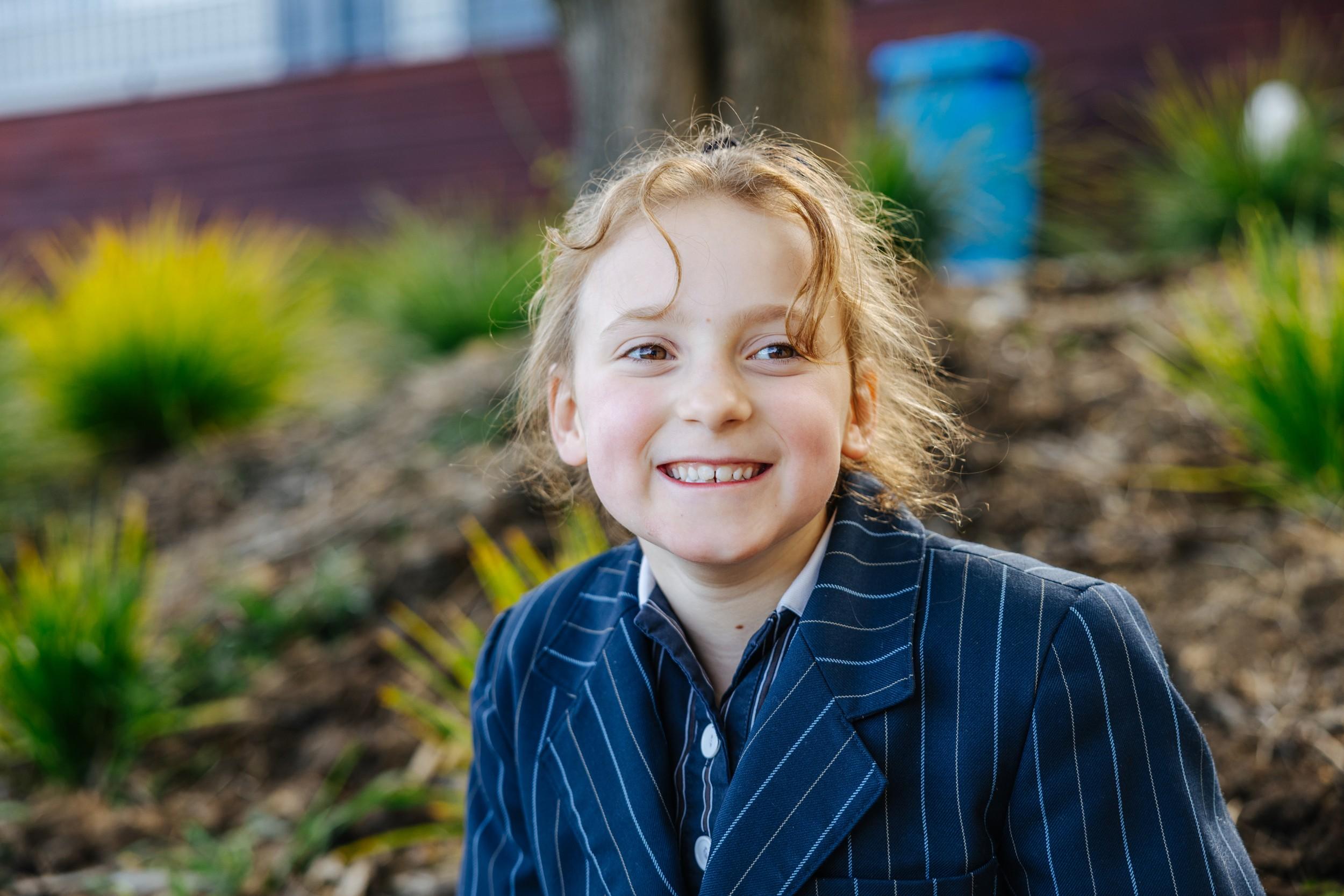 A Primary student at ACC Hobart smiling outdoors at the Geilston Bay campus.