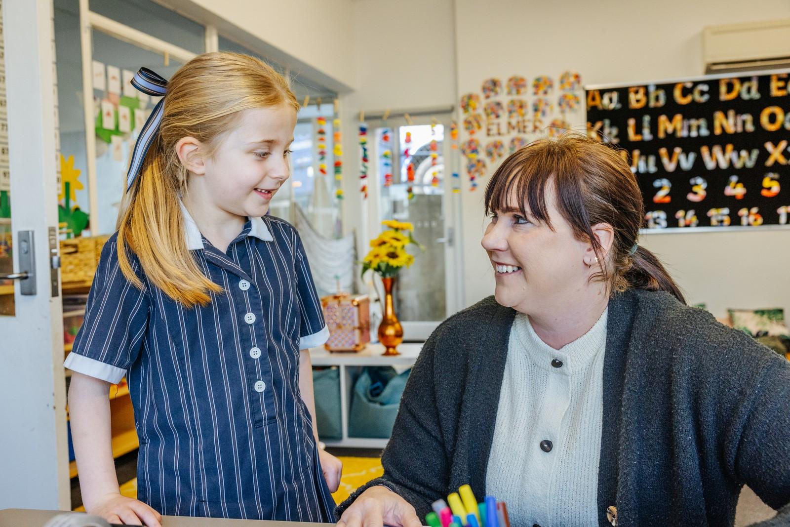 Primary student smiling with her teacher in a classroom at Geilston Bay